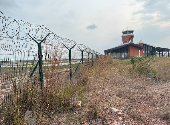 An airport control tower and razor wire fence along an airport runway in Dara Sakor, Cambodia. Photo by Erin West, Operation Shamrock, February 2025
