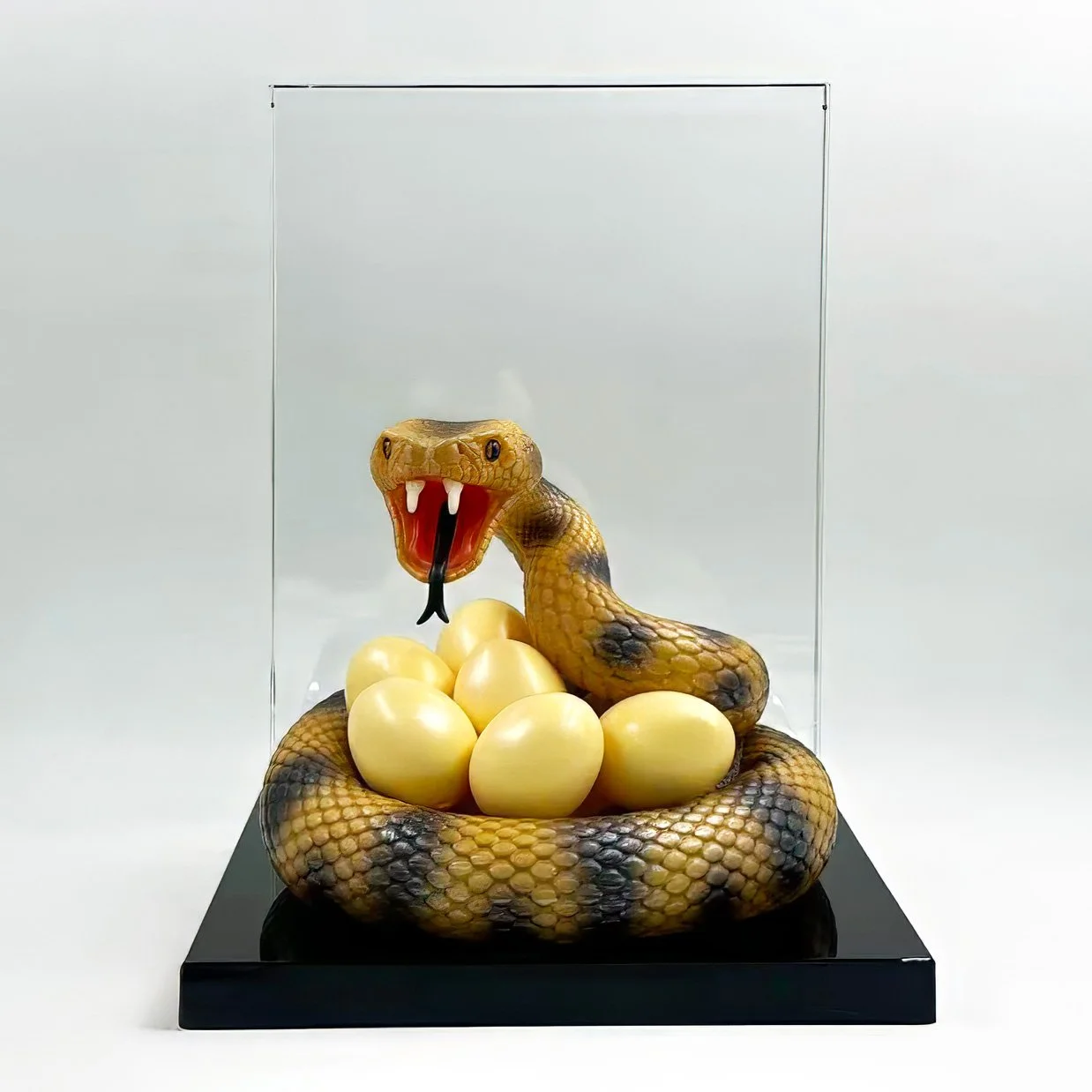 Resin snake sculpture protecting eggs mounted before crystal financial tombstone panel.