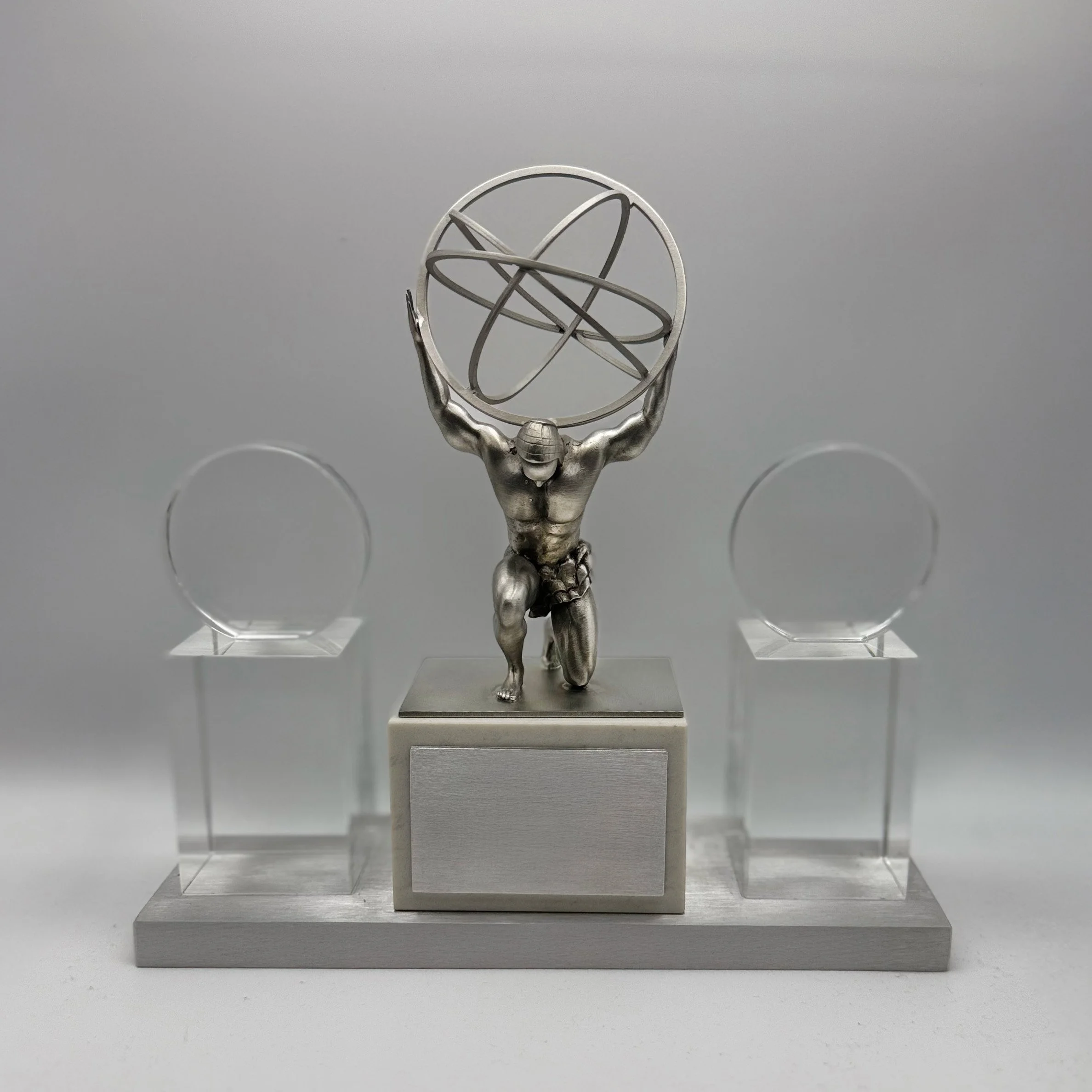 Custom corporate award featuring a metallic Atlas sculpture holding an orbital globe between two clear crystal panels.
