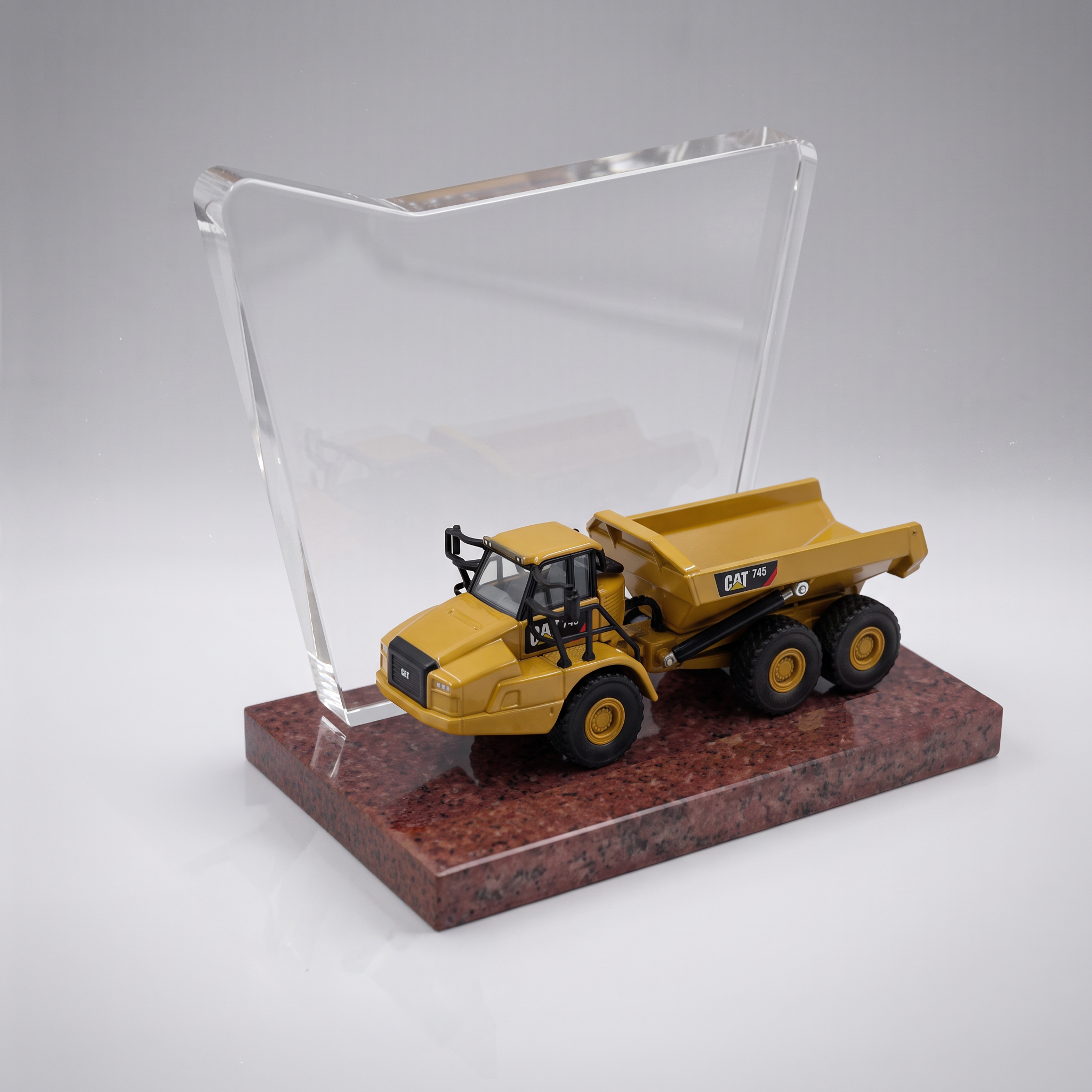 Custom construction deal toy featuring a yellow articulated dump truck, clear award panel and stone base.
