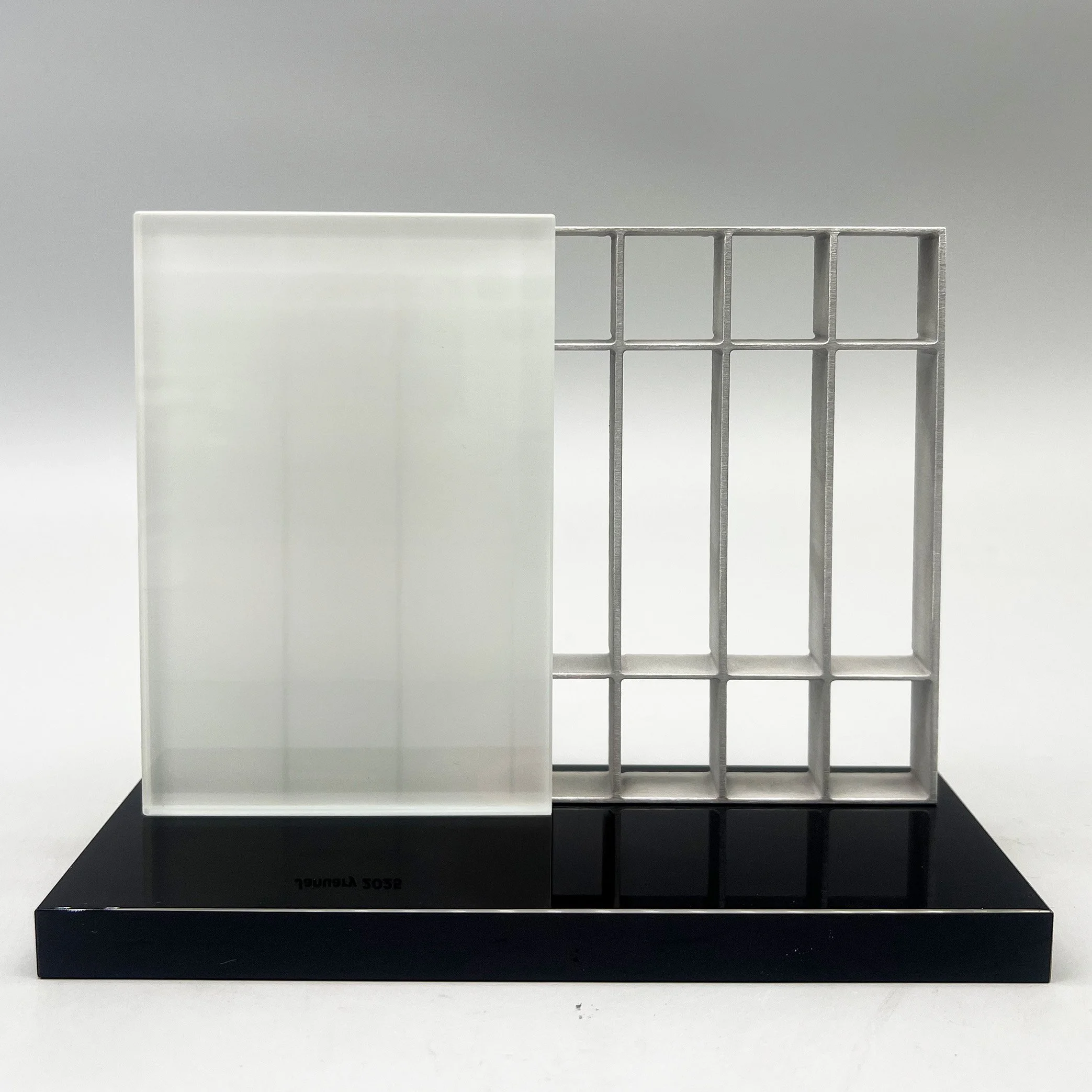 Architectural grid composition in Lucite, translating structure and proportion into a restrained commemorative form.