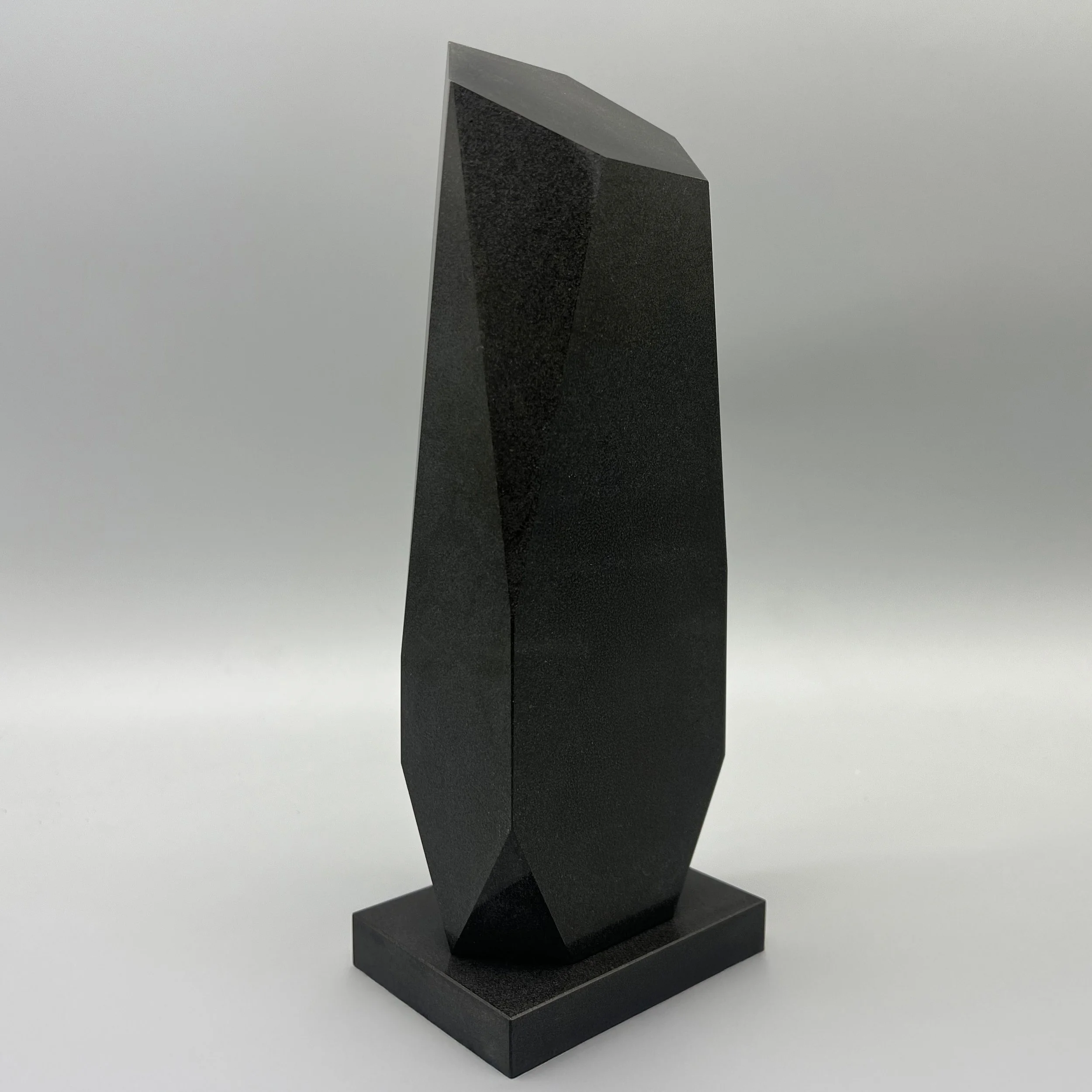 Tall faceted black onyx obelisk corporate award shown at an angle on a matching base.
