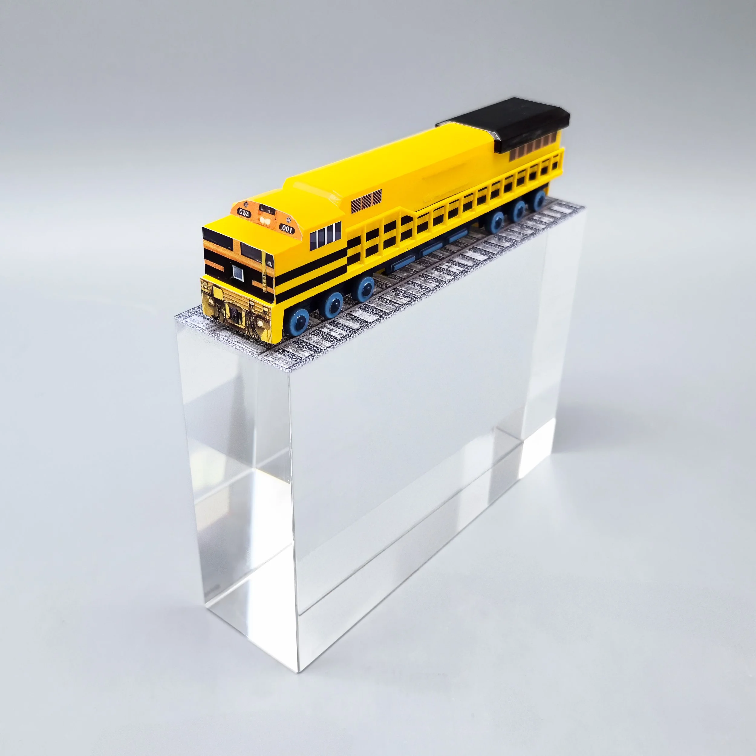 Custom railroad deal toy featuring a yellow locomotive and track mounted on a clear Lucite block.