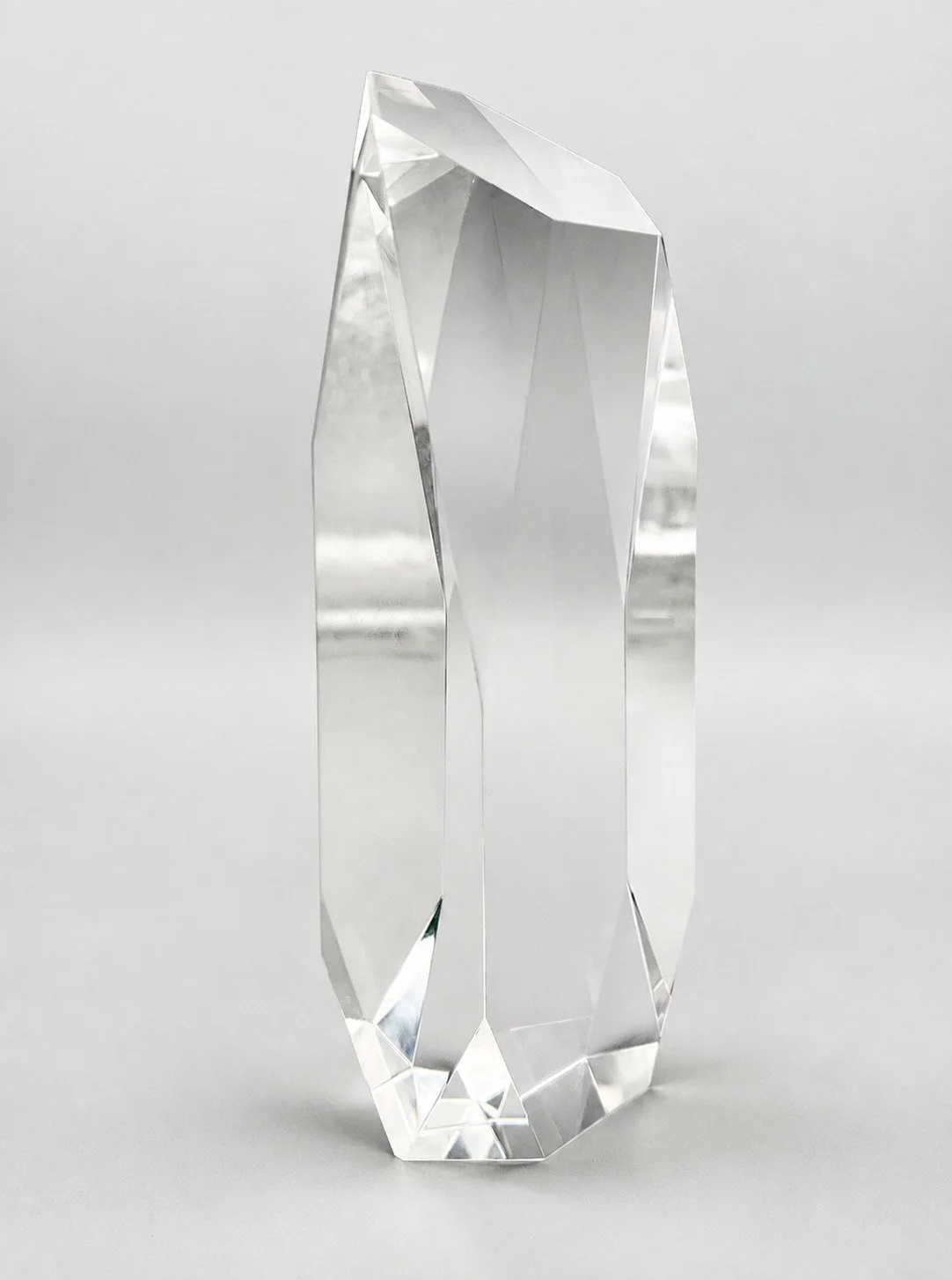 Clear faceted crystal award with an asymmetrical top and polished edges.