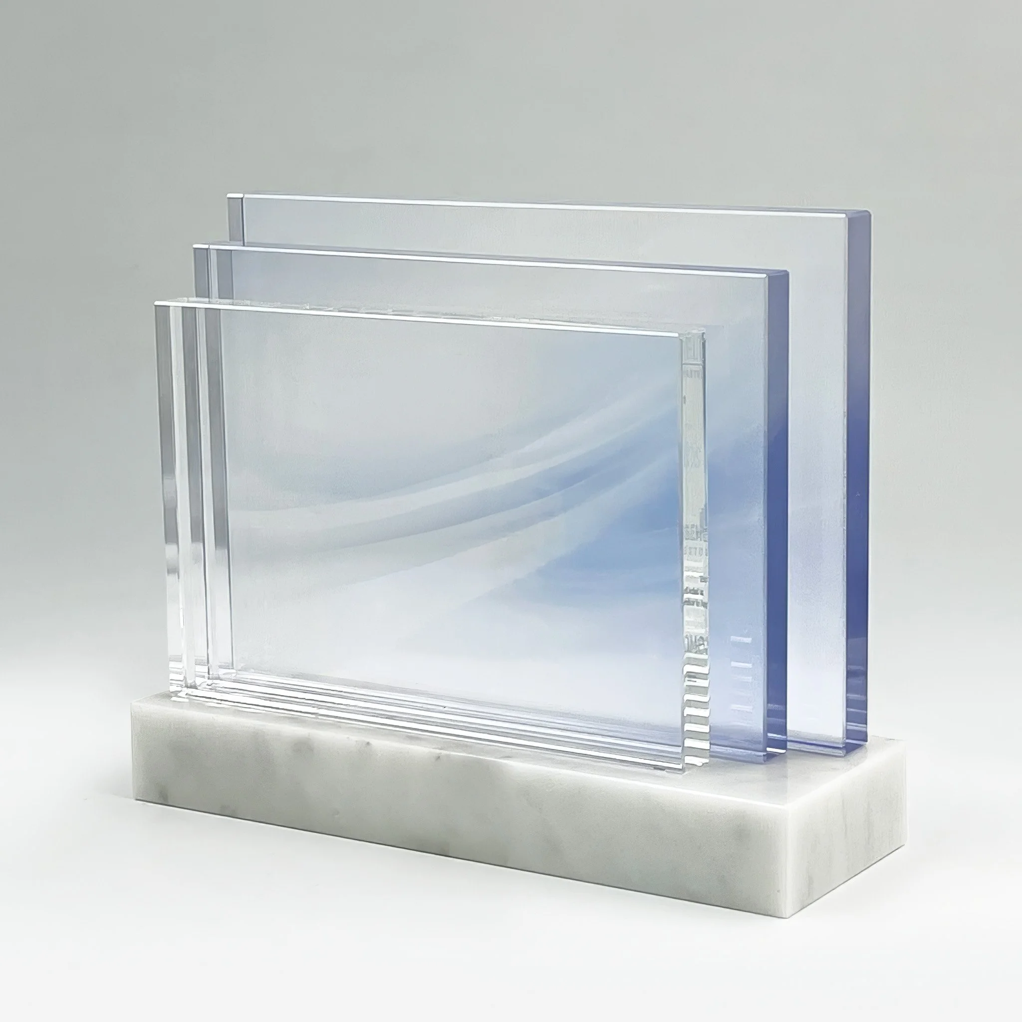 Custom corporate award with three overlapping clear and blue-tinted crystal panels on a silver base.