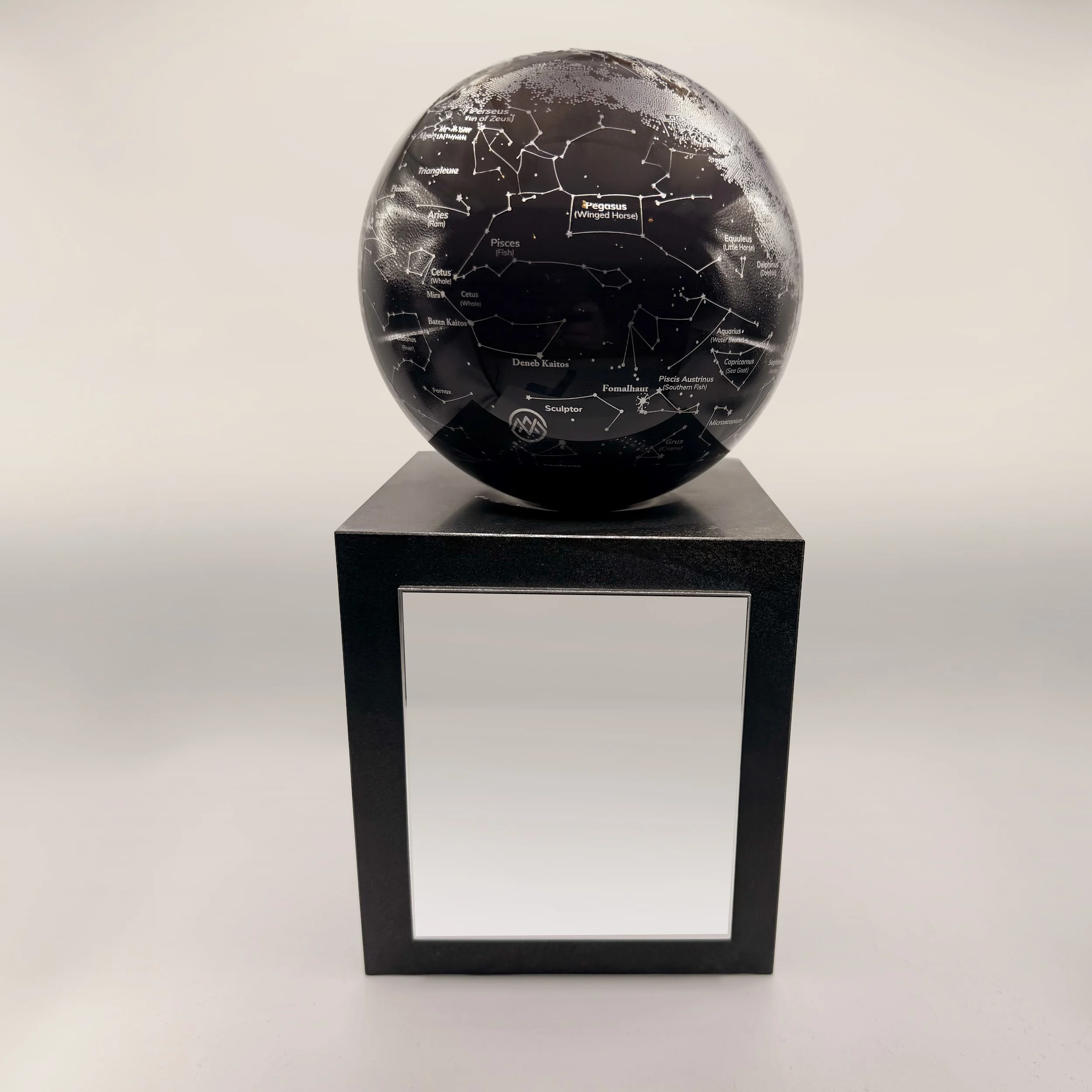 Black rotating constellation globe mounted on stone base with etched star maps representing global reach and strategic vision in executive deal toy design.