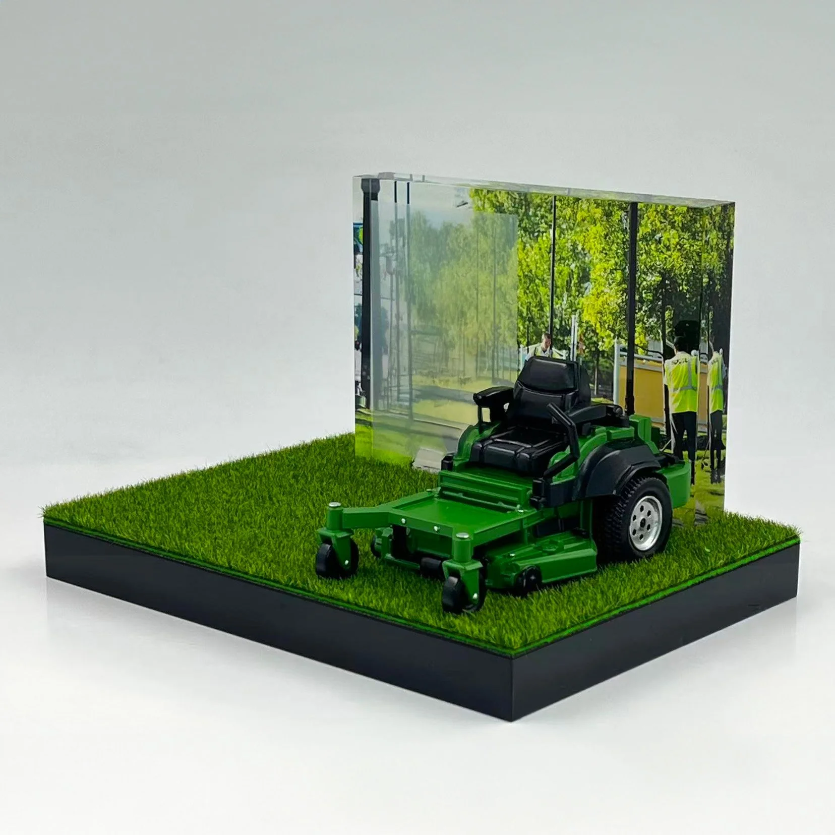 Riding lawn mower model on grass base with landscape photo backdrop