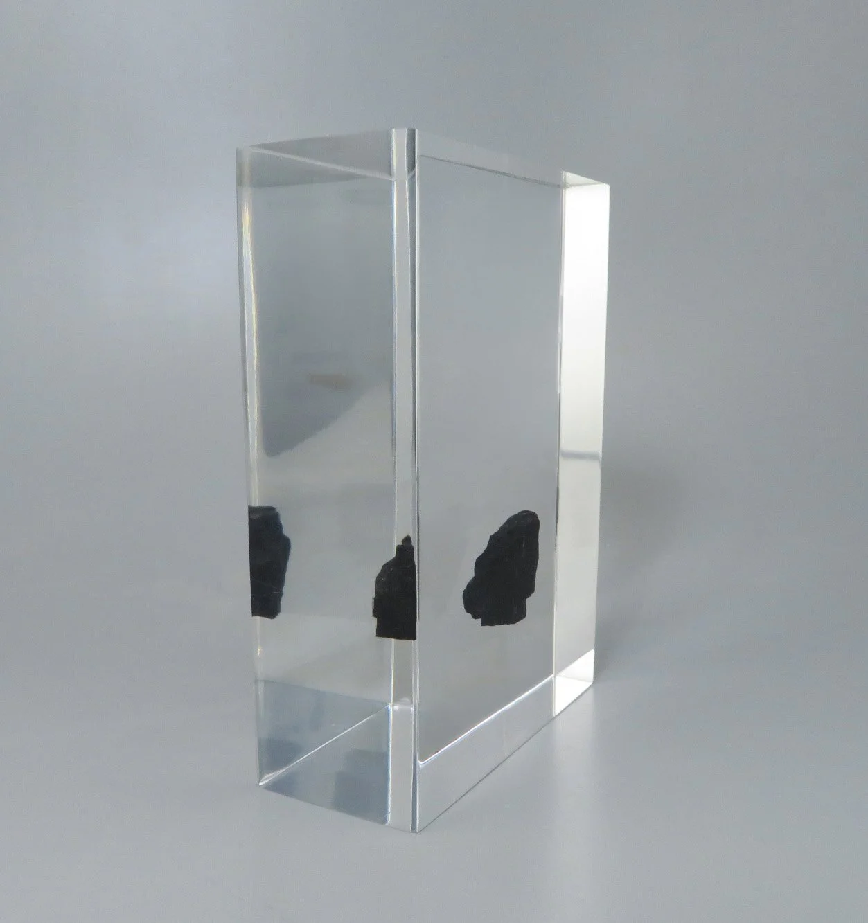 Clear Lucite financial tombstone with pieces of coal embedded inside a tall rectangular form.