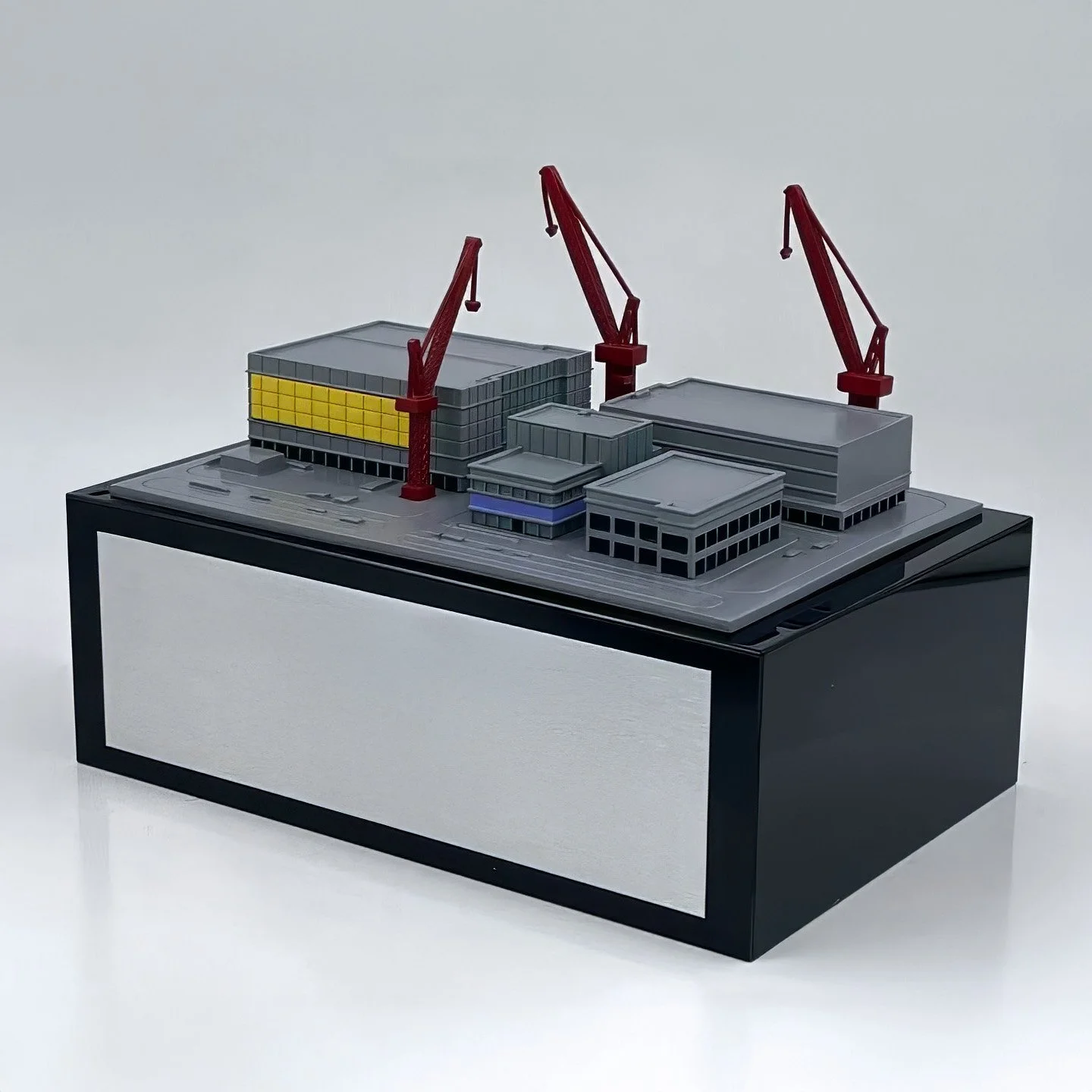 Miniature semiconductor fabrication plant with cranes and facility details on a rectangular base.