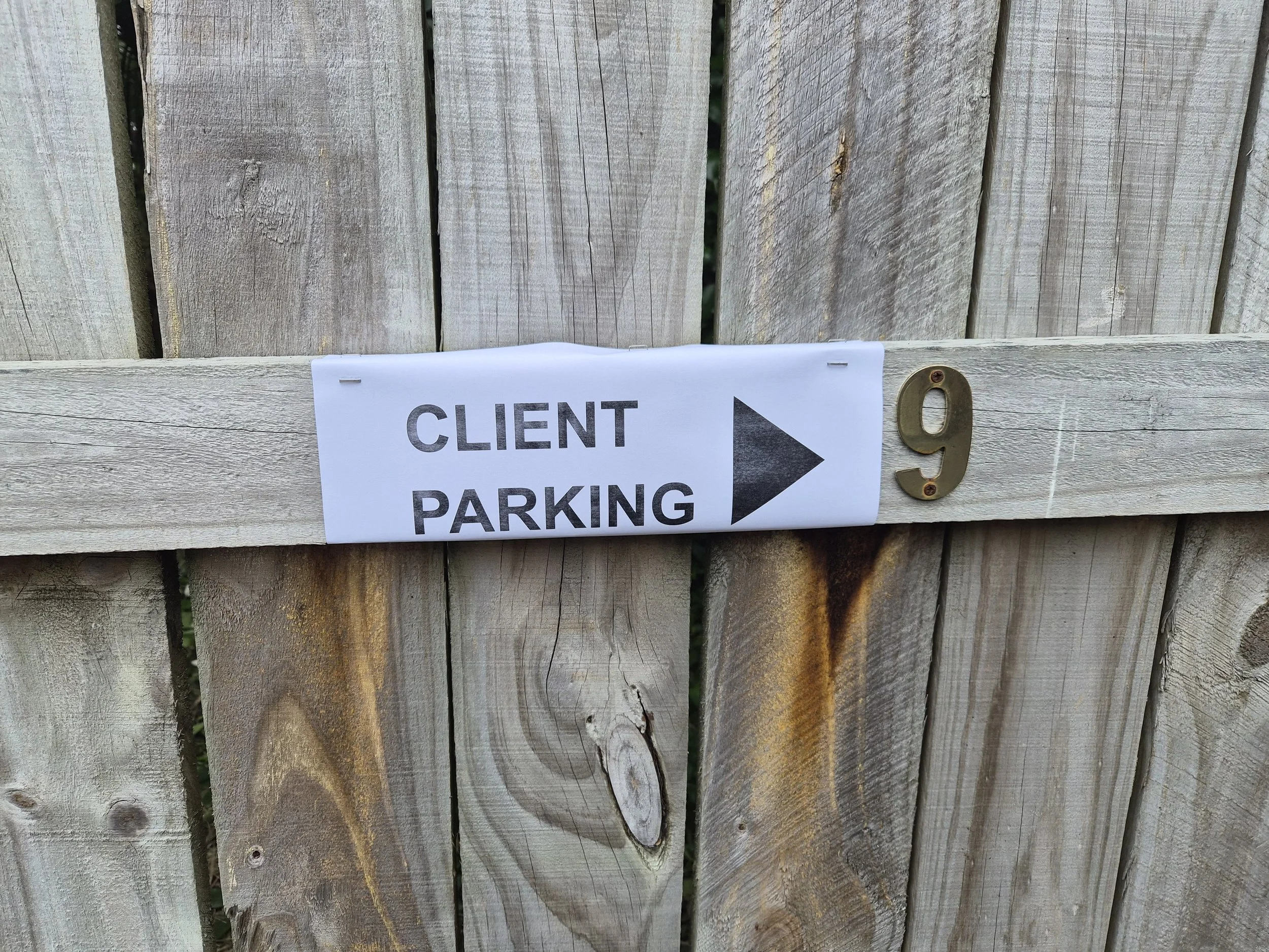 Wooden fence, with Client Parking sign and number 9 marking the designated clinic parking space.