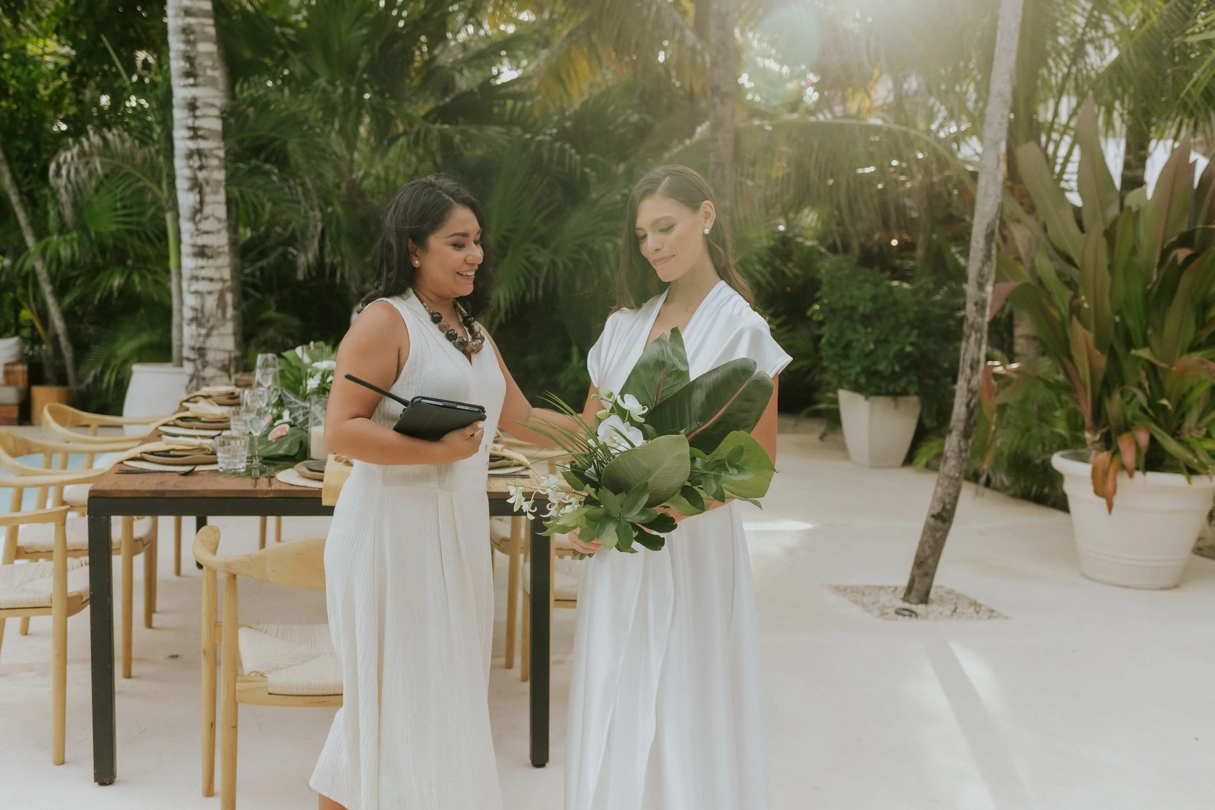 Wedding Coordinator helping the bride to arrange the bouquet in her hands with a green background and table scape wedding