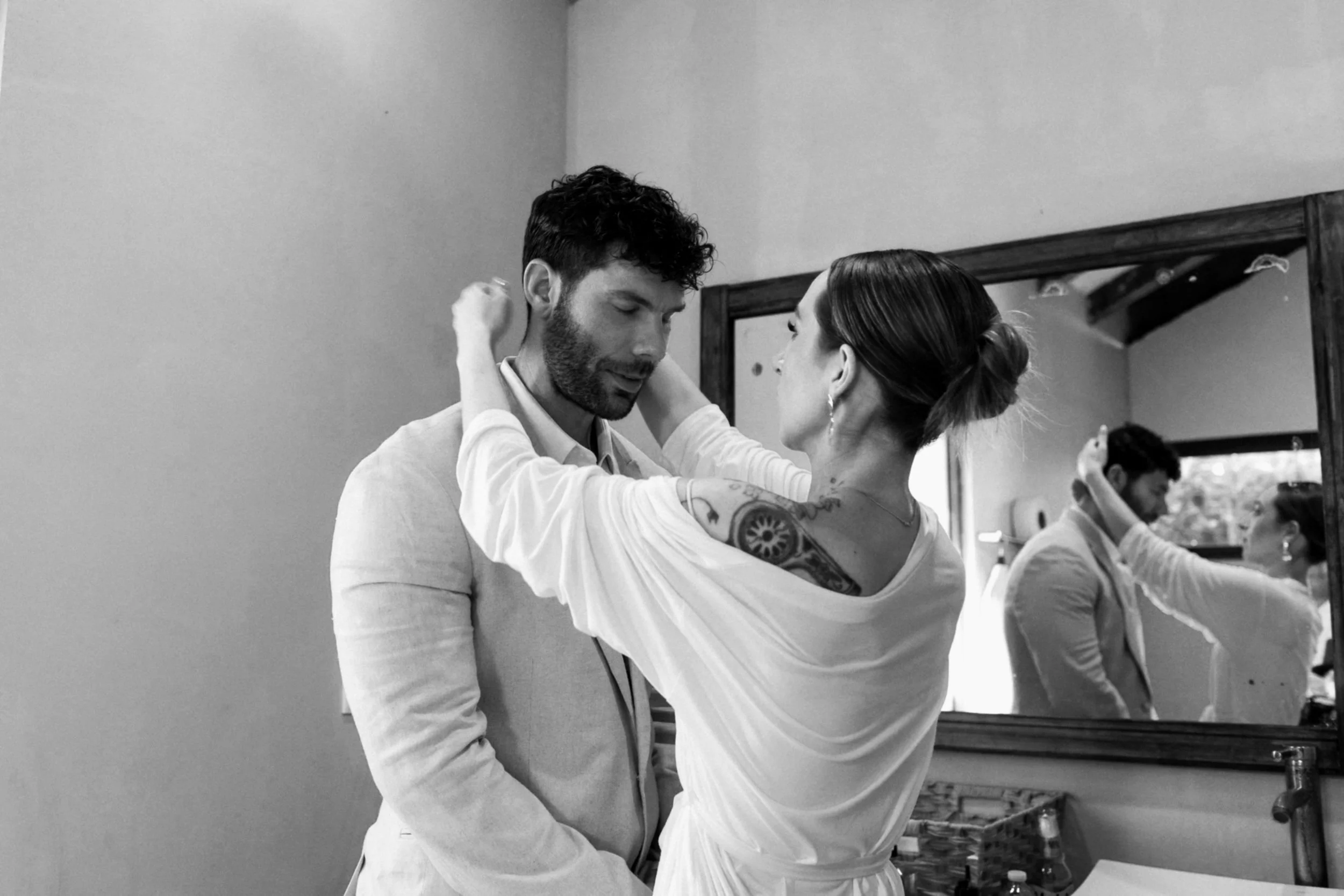 the bride adjusting the hair of the groom in their wedding at blue venado pamuul in mexico at the bridal suit