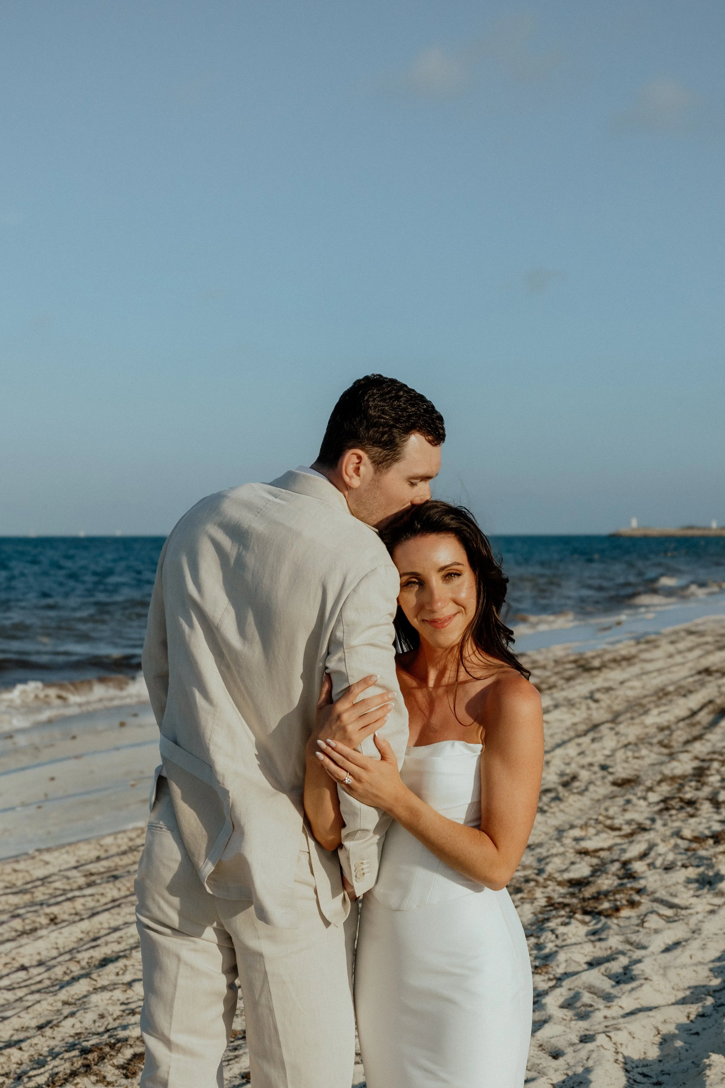 The romantic session beach front on playa mujeres finest resort the beautiful couple posing in their wedding atire being happy and lovely together at their romantic session with the wedding photographer using a 24-70mm canon lens