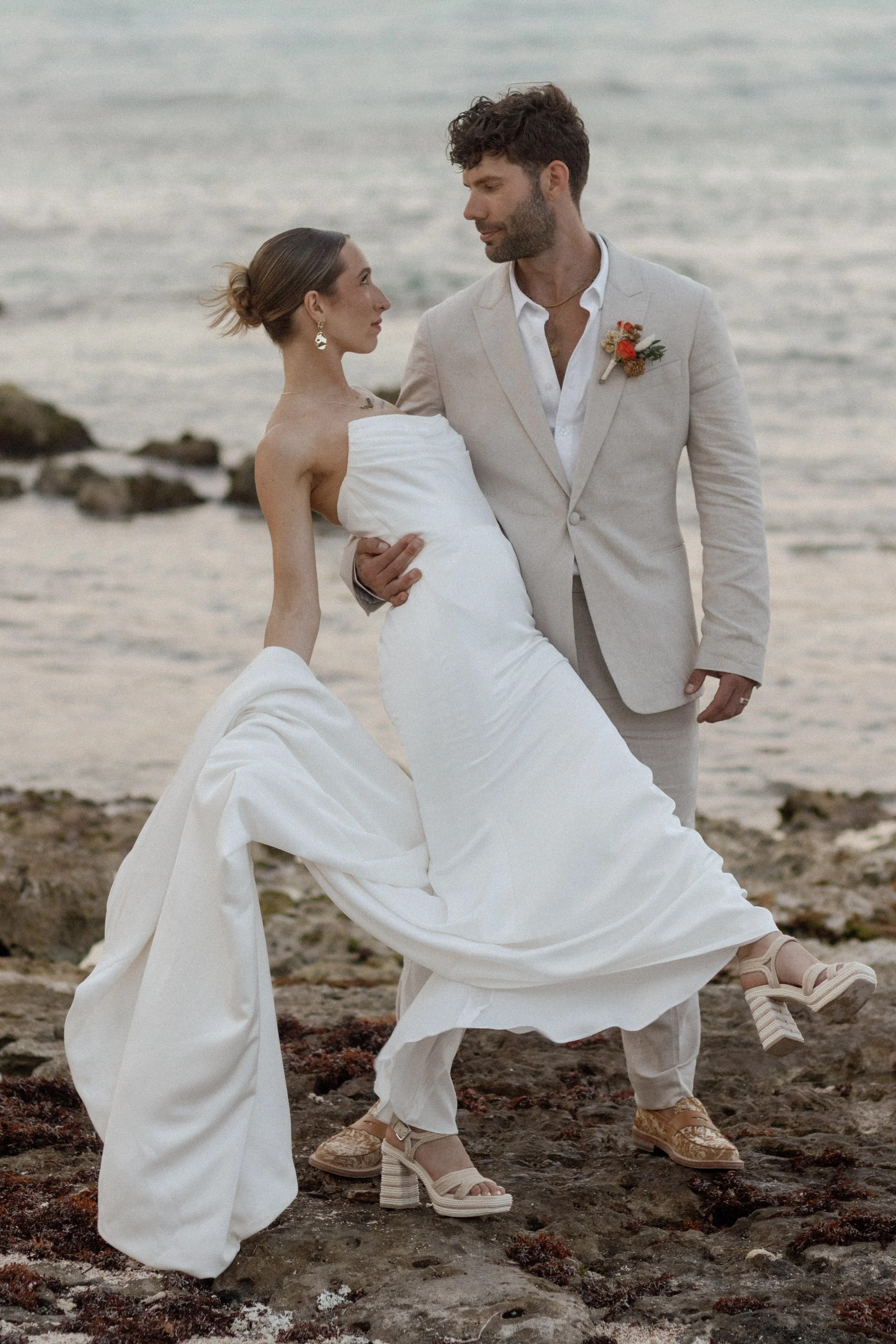 The groom sweeping his bride off her feet against the stunning backdrop of the ocean. A playful, romantic moment captured forever in the shores of mexico in blue venado paamul riviera maya
