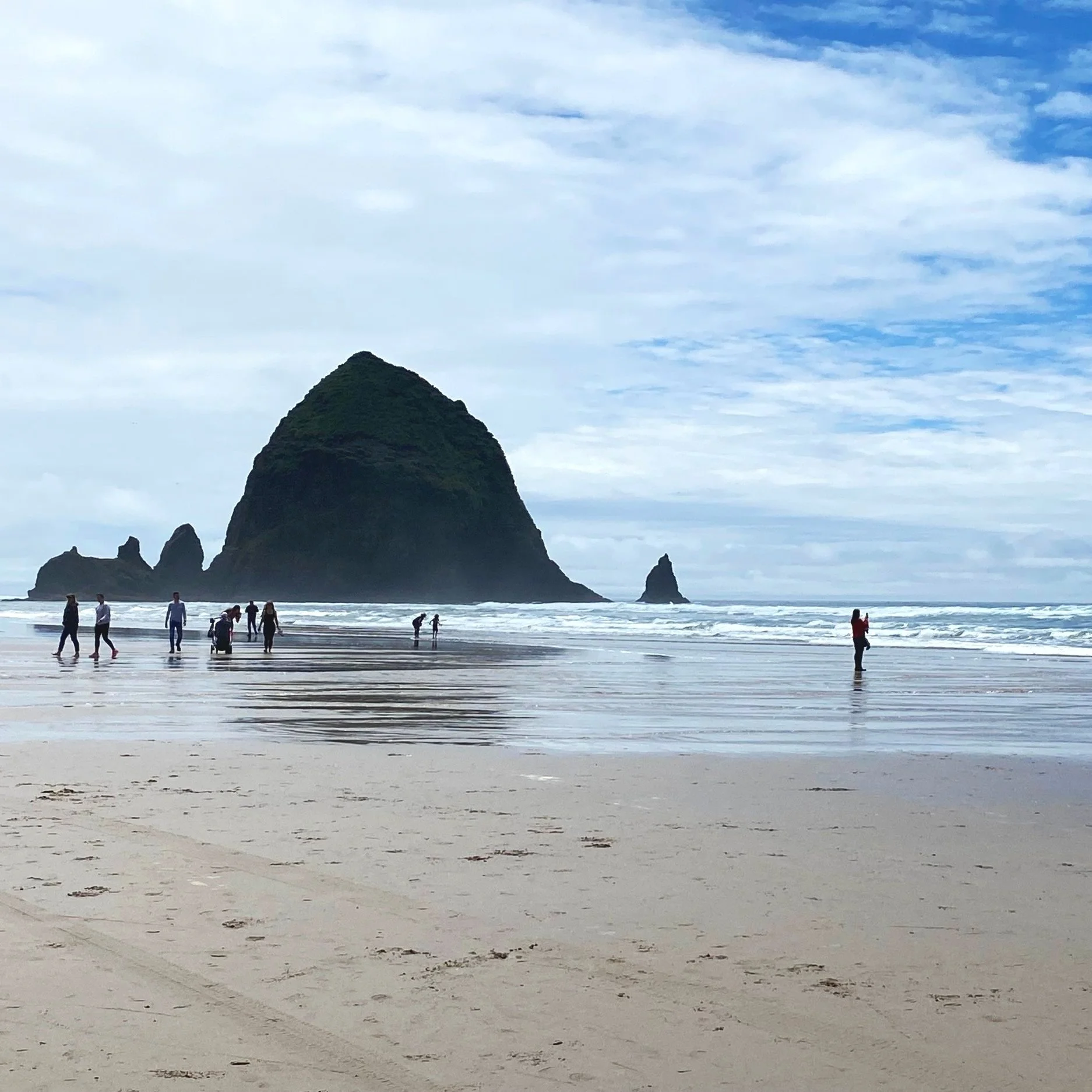 A photo of a rock formation known as "Haystack Rock" on a beach on Cannon beach on the Oregon Coast.