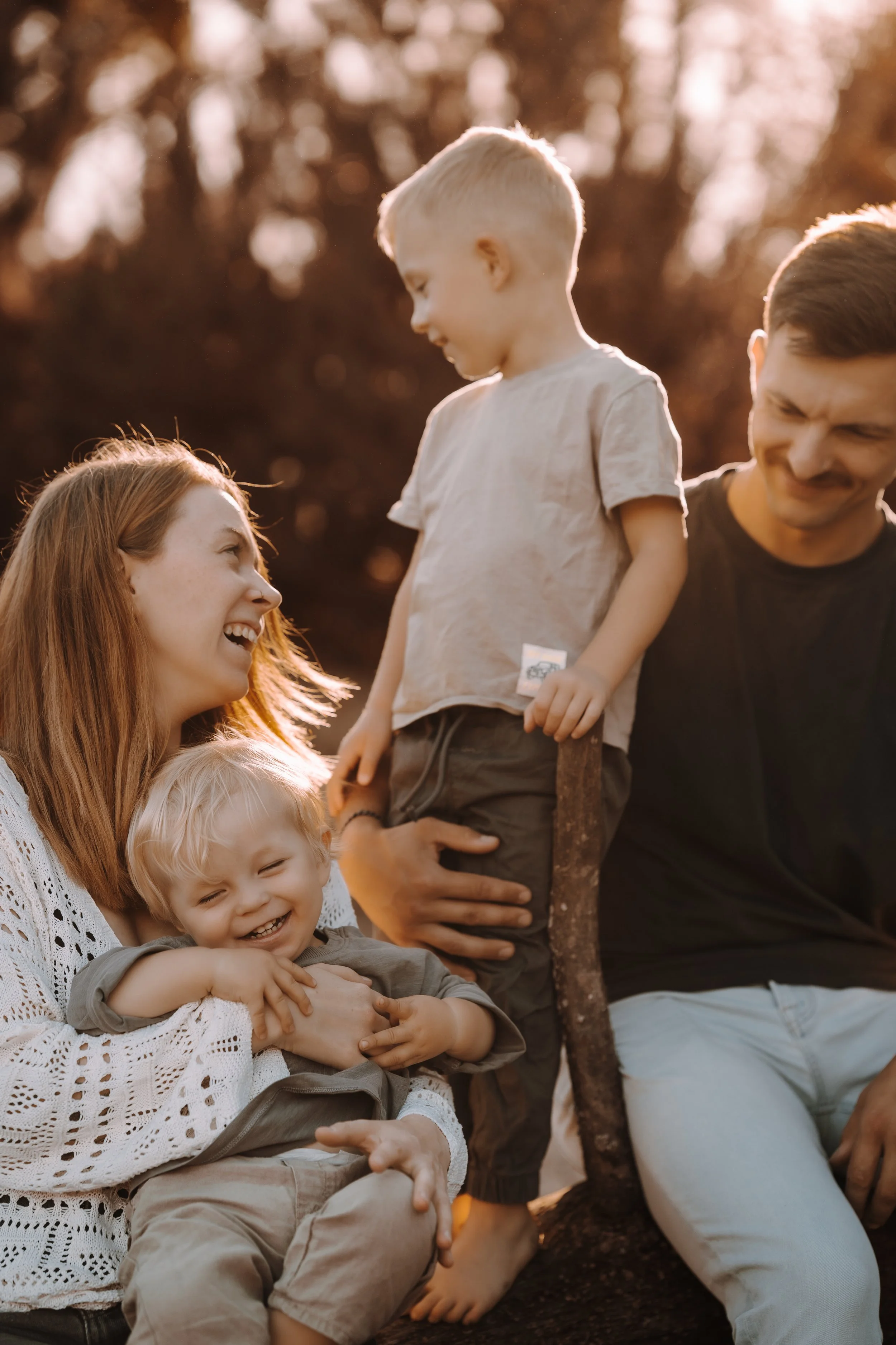 Familie im Freien beim Lachen und Umarmen, Sonnenlicht, Herbstfarben im Hintergrund.