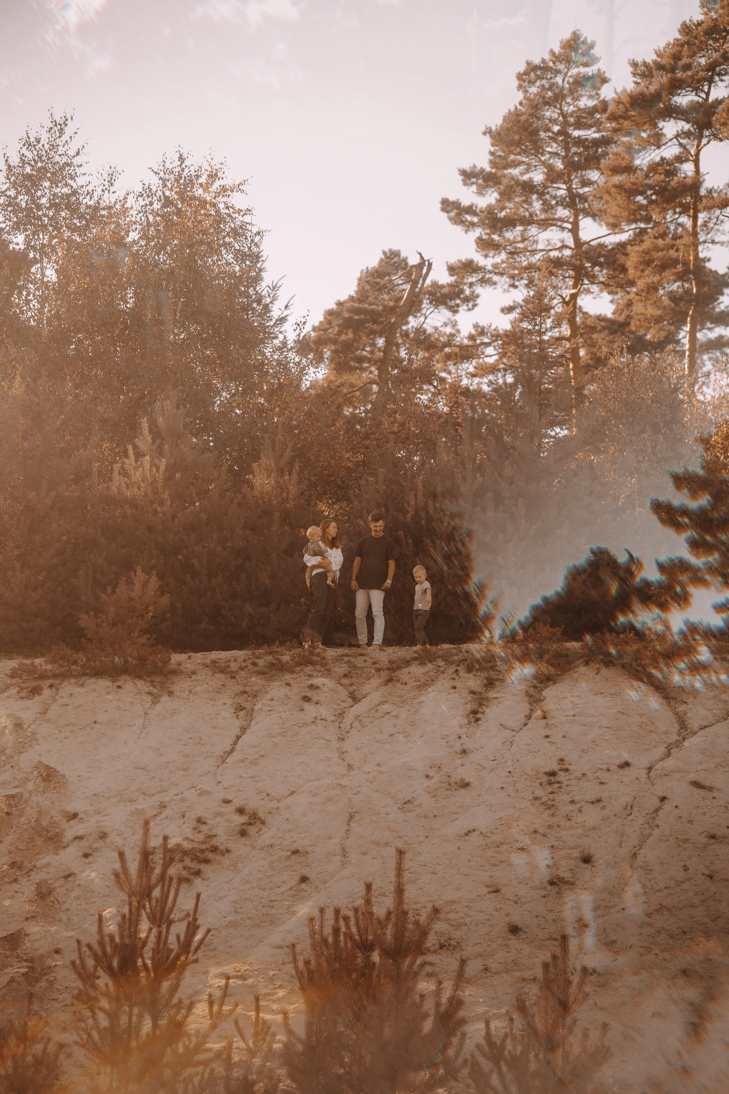 Familie mit Kindern beim Spaziergang im Wald bei Sonnenuntergang.