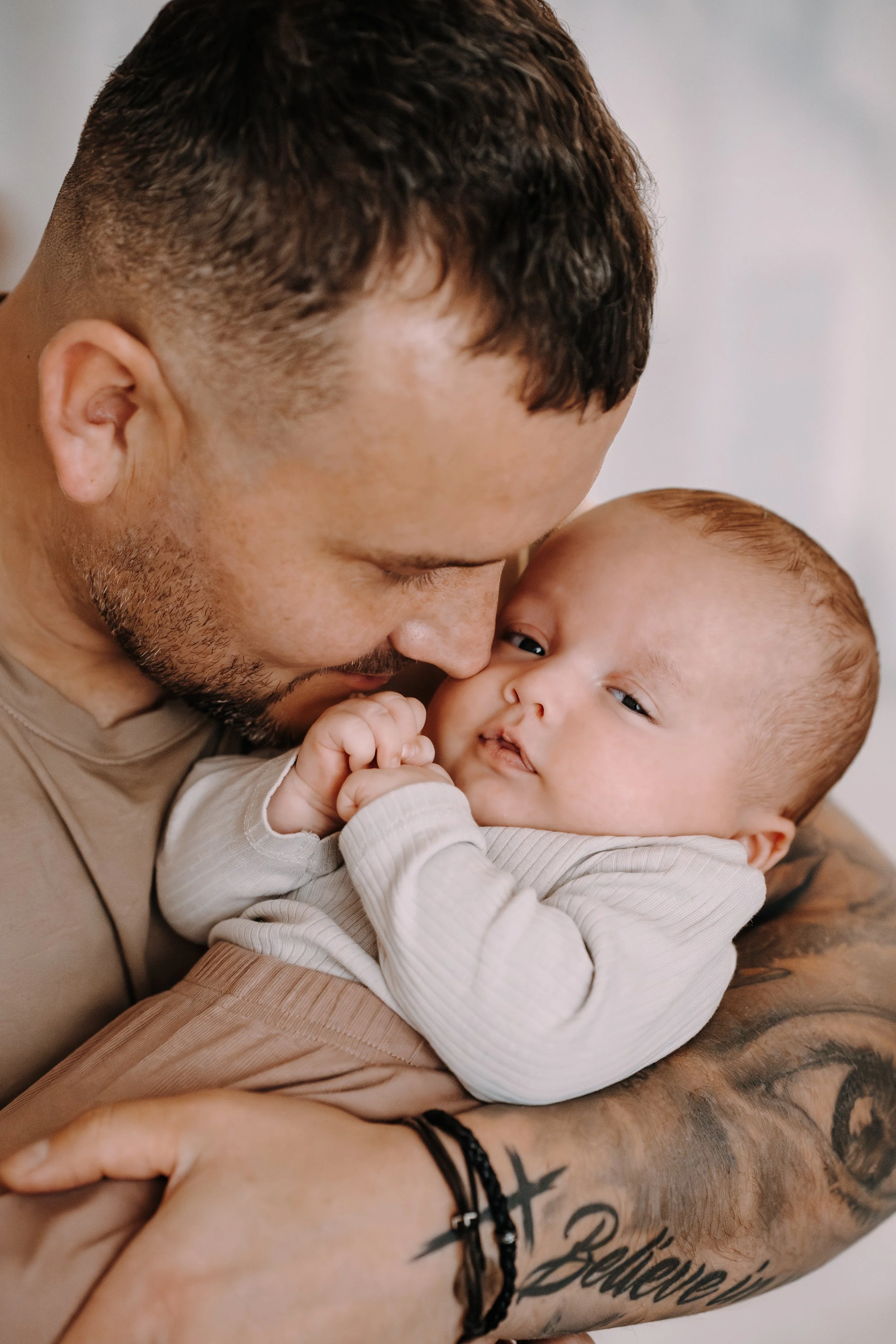 Ein Mann hält ein Baby im Arm und zeigt Zuneigung, indem er seine Stirn an die des Babys presst.