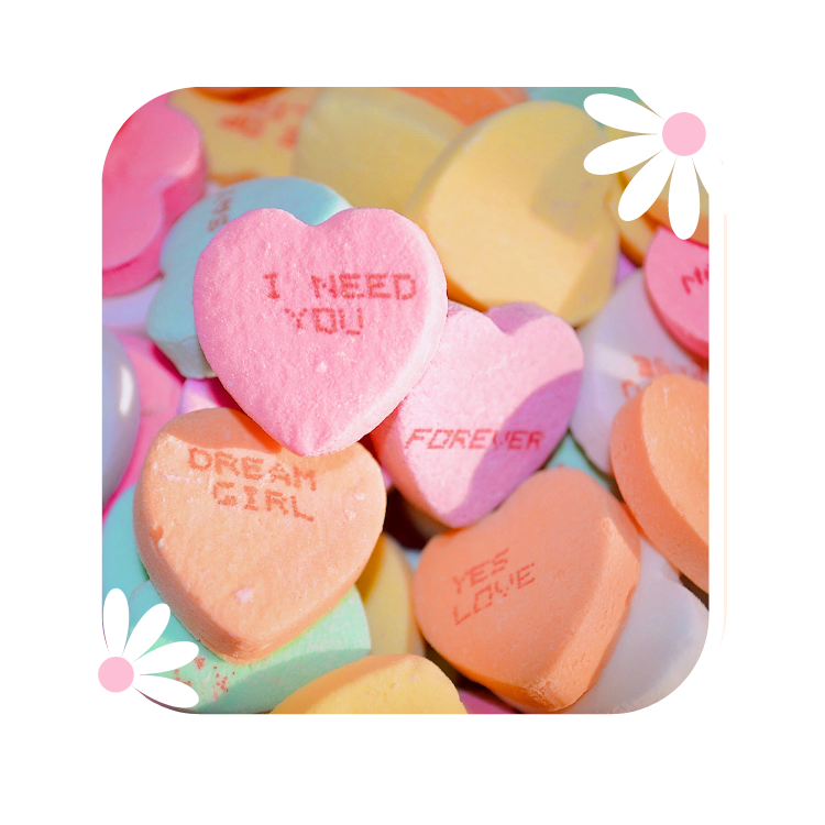Colorful heart-shaped candies with romantic messages such as "I NEED YOU," "FOREVER," "DREAM GIRL," and "YES LOVE"