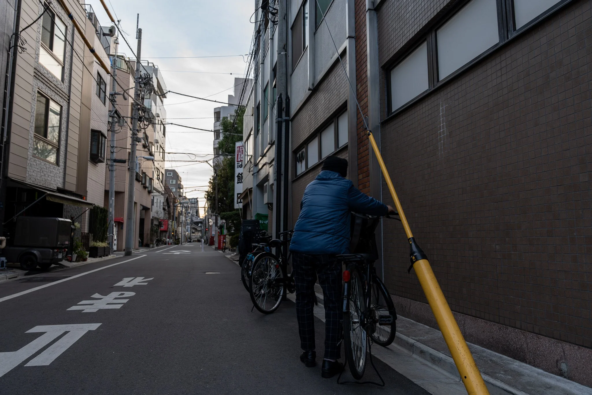 Tokyo side street near Imanari Jiu-Jitsu with a cyclist walking a bicycle