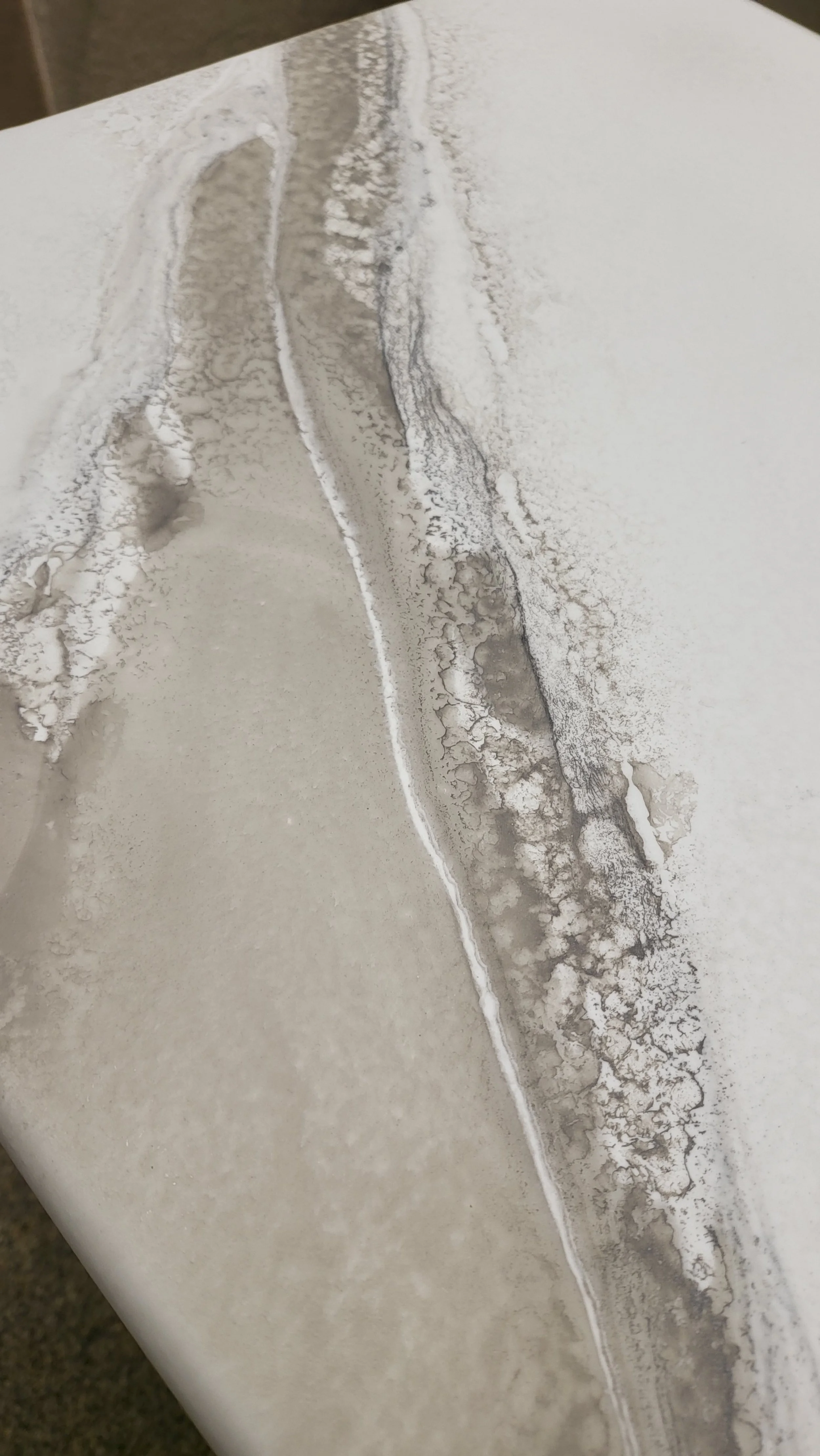 Close-up of a white epoxy lecture hall table with gray and black abstract patterns, resembling a textured or marbled artwork.