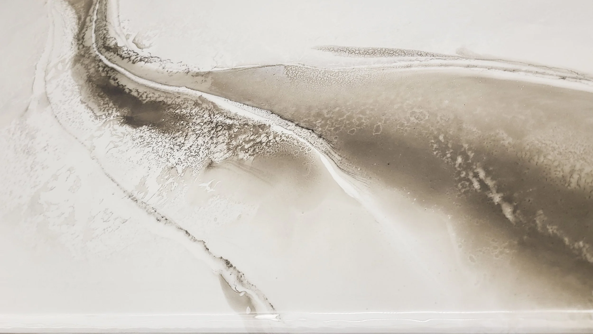 Close image of a epoxy table top with swirling shades of beige, gray, and white, resembling a textured marble or stone surface.
