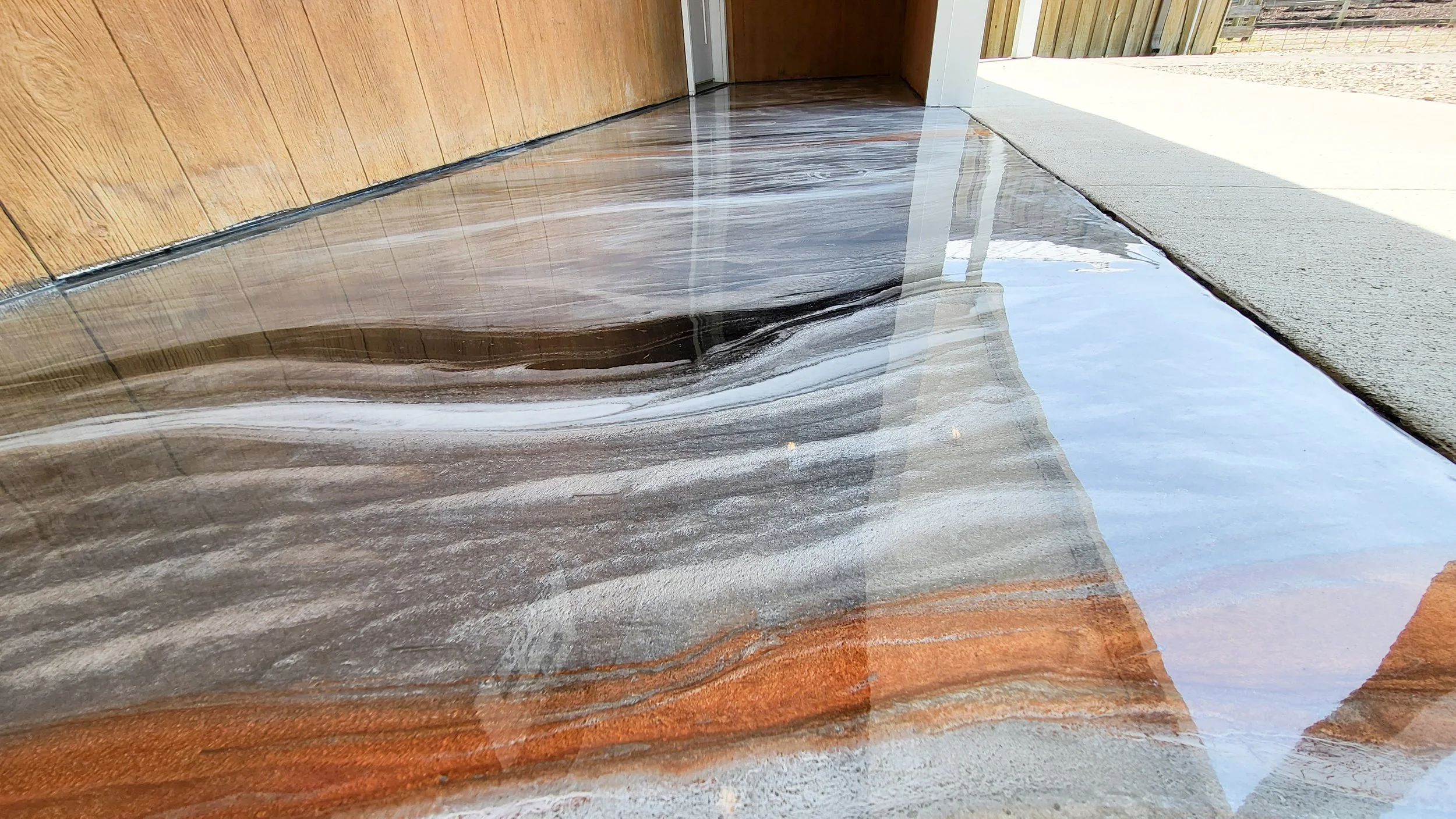 Outside bathroom entrance with a marbleized grey epoxy floor with copper, whit and black highlights.