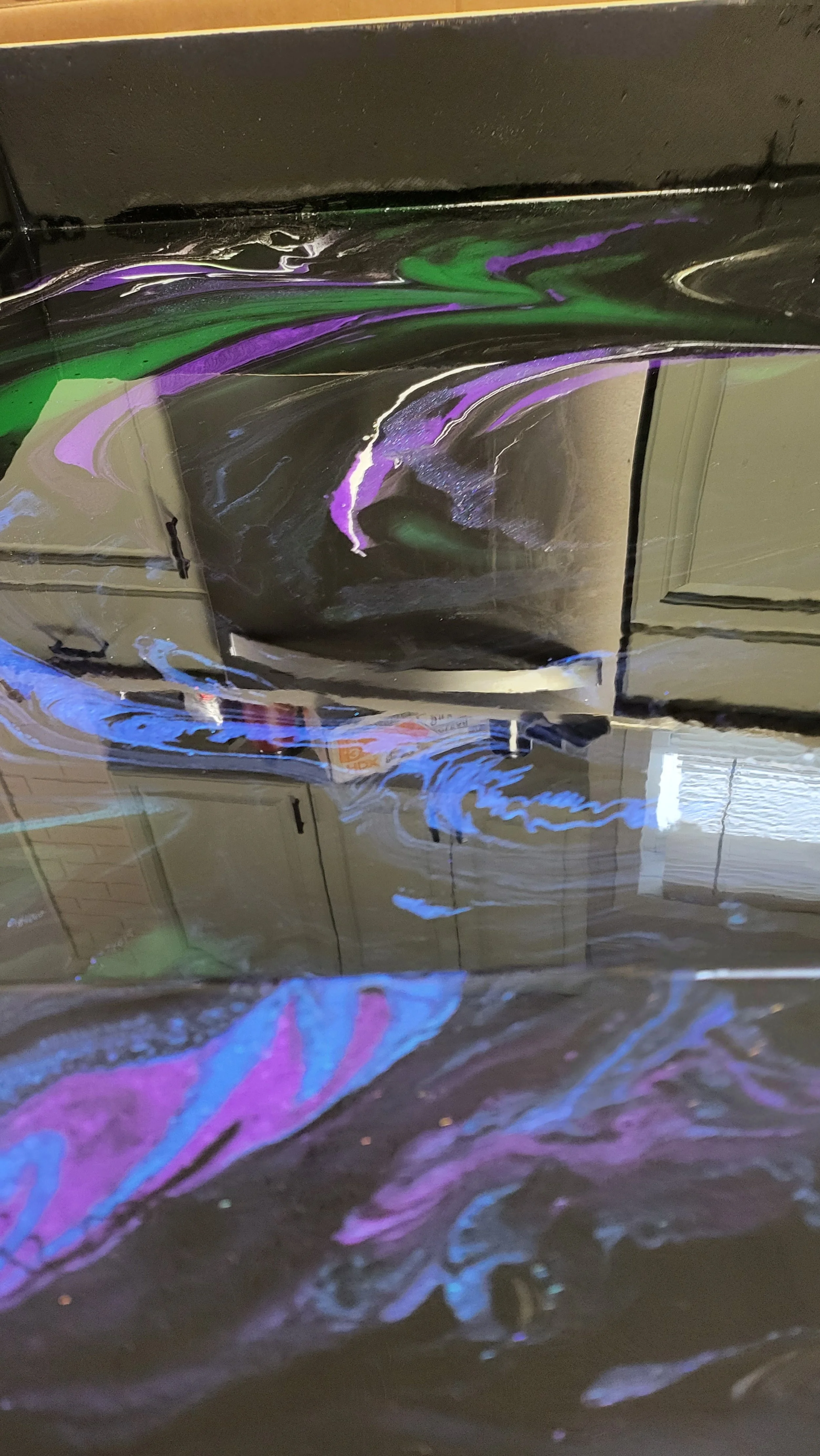 Colorful swirl epoxy pattern, with reflections of a window and kitchen cabinets.