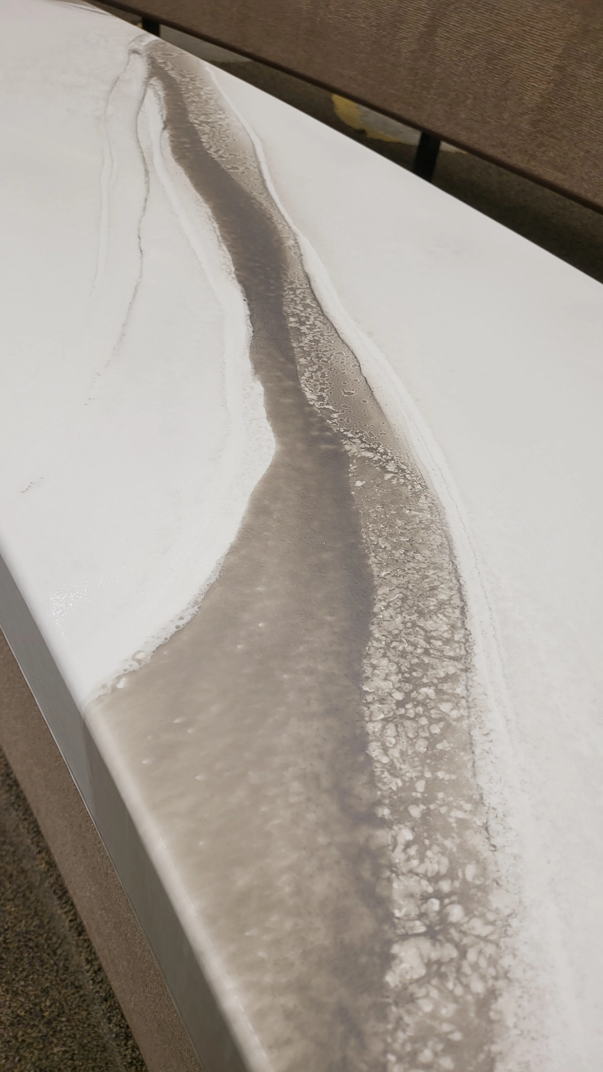 Close-up view of a white epoxy countertop with grayish-brown highlights that run across the surface.
