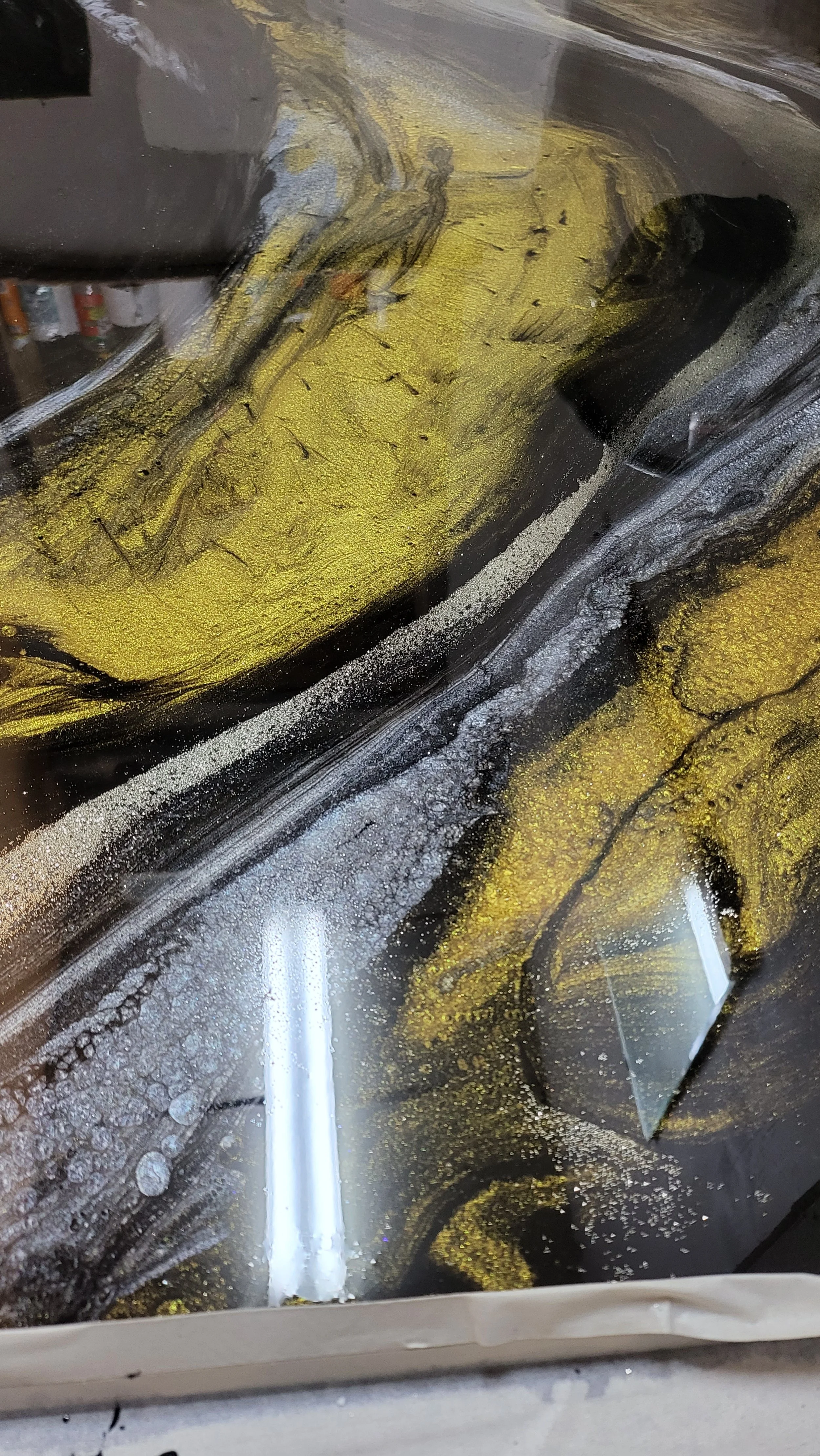 A close-up view of a epoxy floor with black, gold, and white swirling patterns.