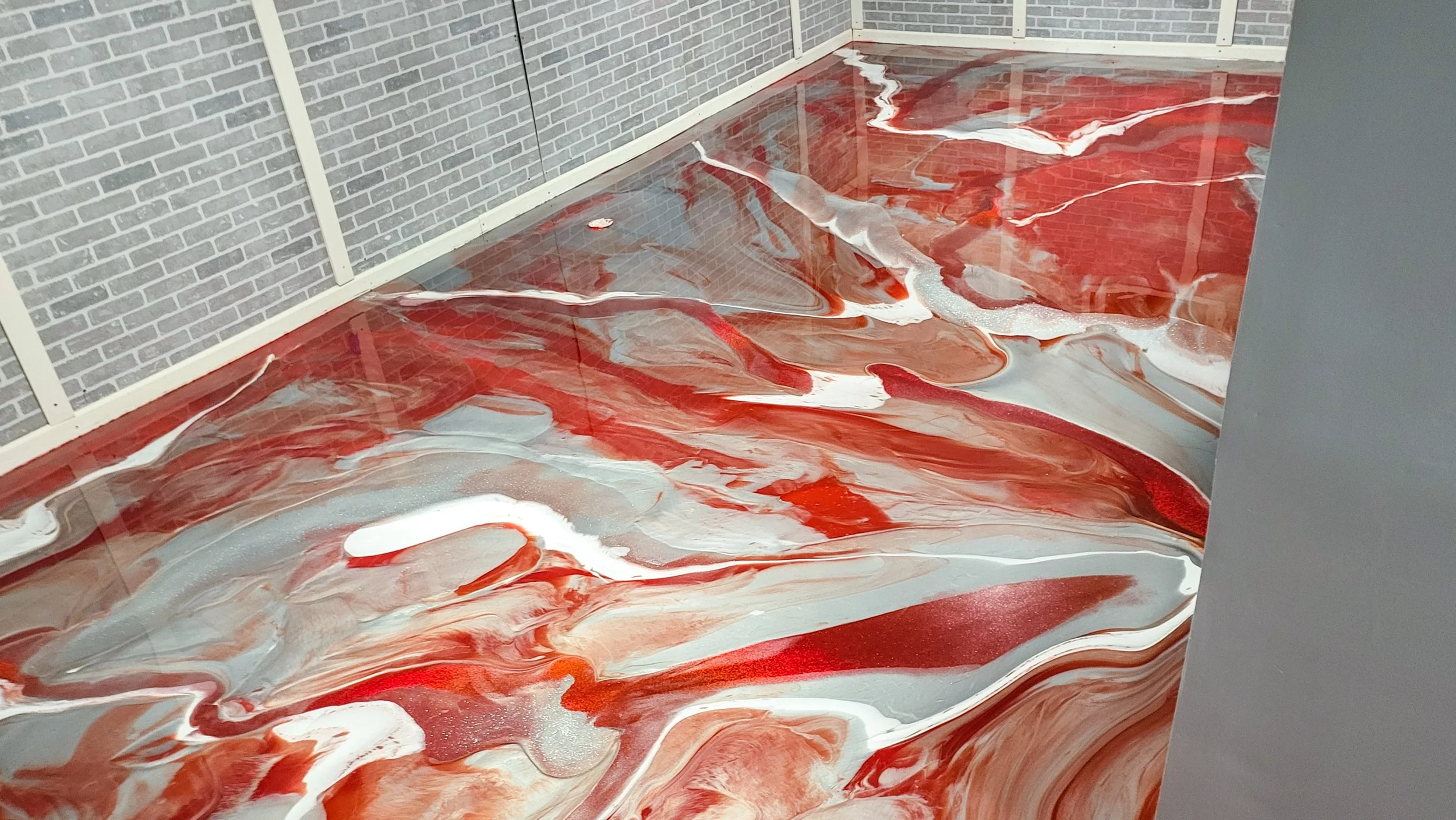 Basement with a epoxy floor featuring a red, white, gray, and silver marble-like pattern.