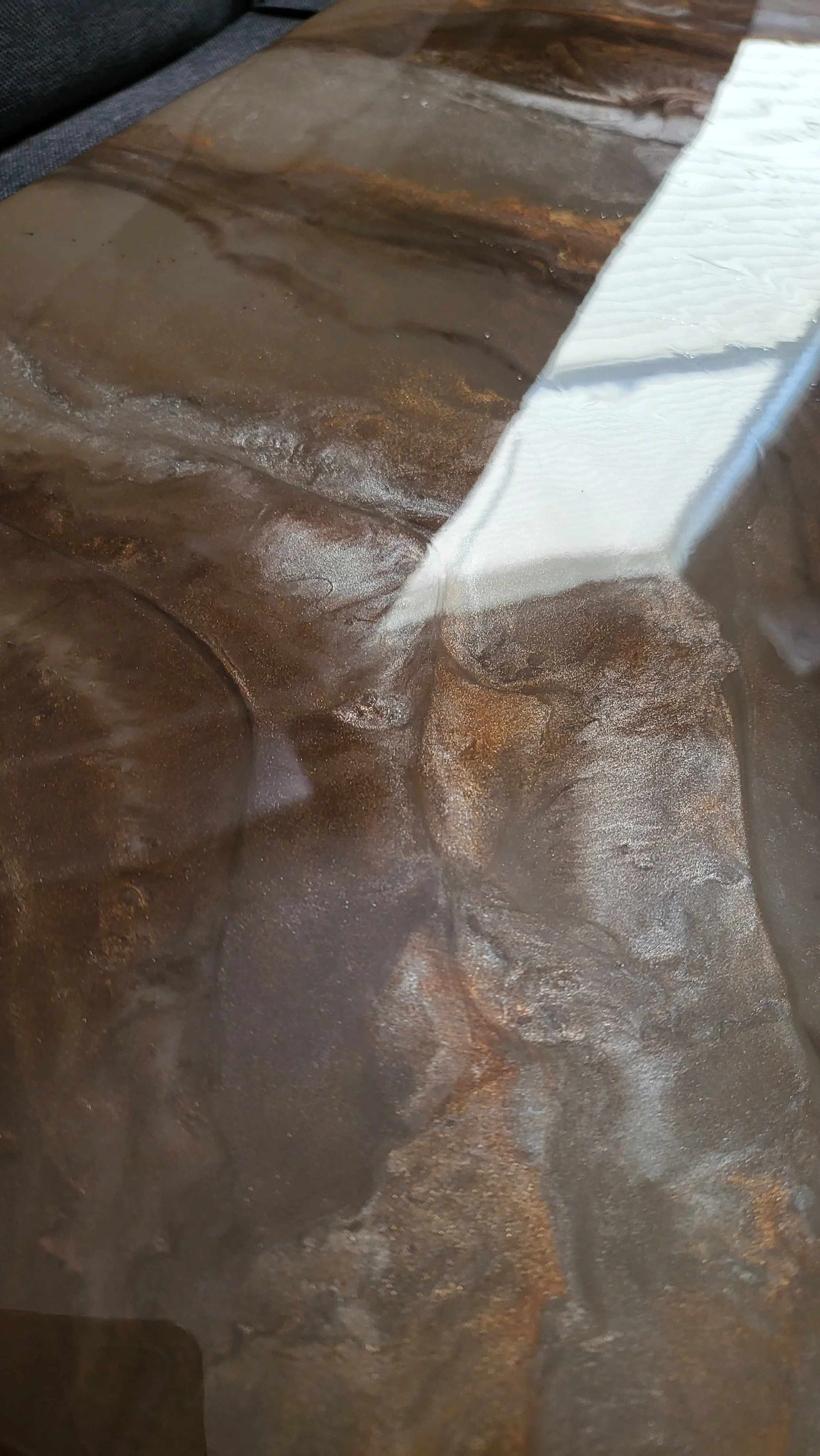 Close-up image of a granite style epoxy kitchen countertop with a light-colored water or epoxy resin streak along the edge.