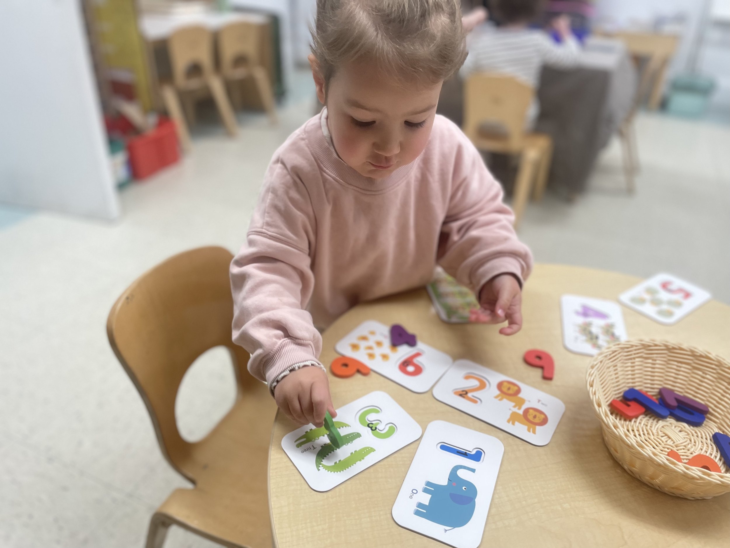 Little girl playing with number and animal cards with a parent's glowing testimonial
