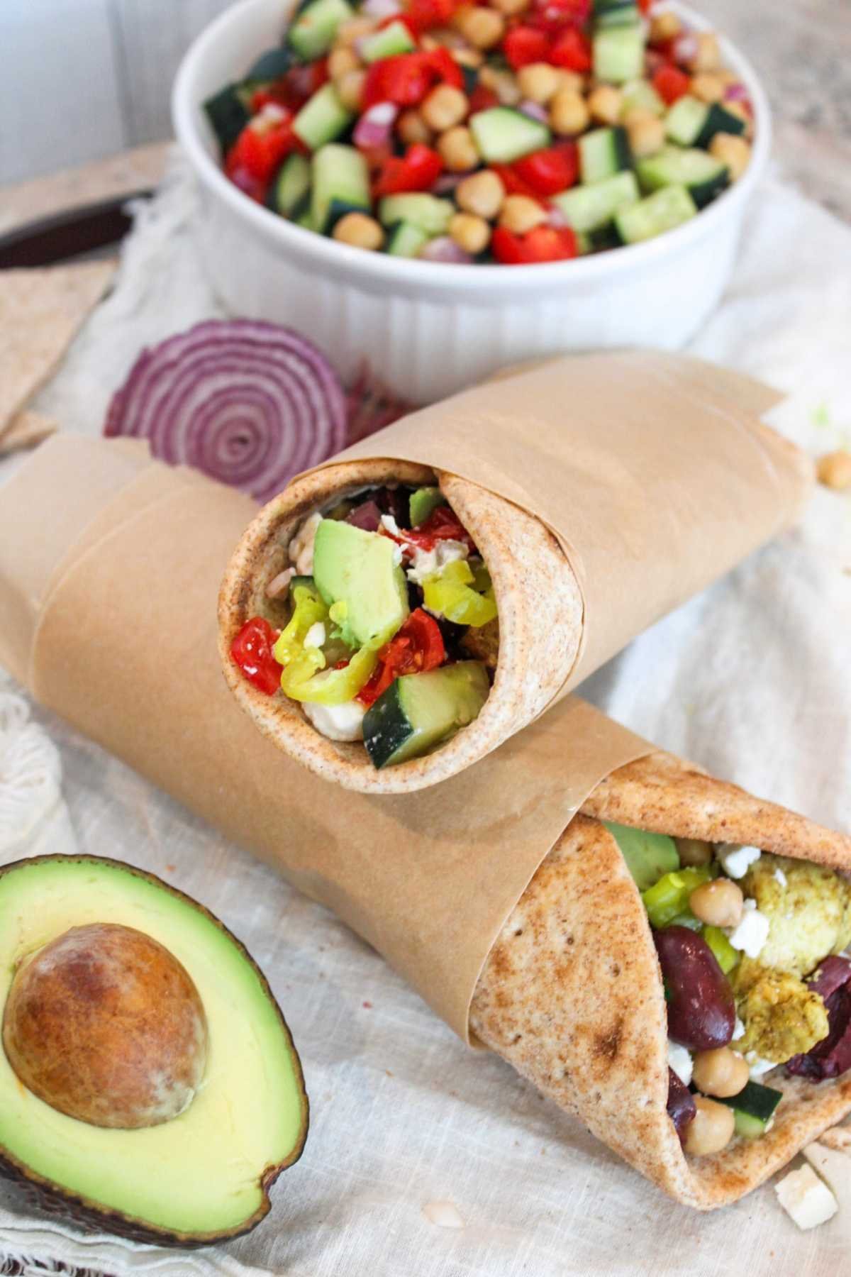 stack of chicken pita wraps next to an avocado.
