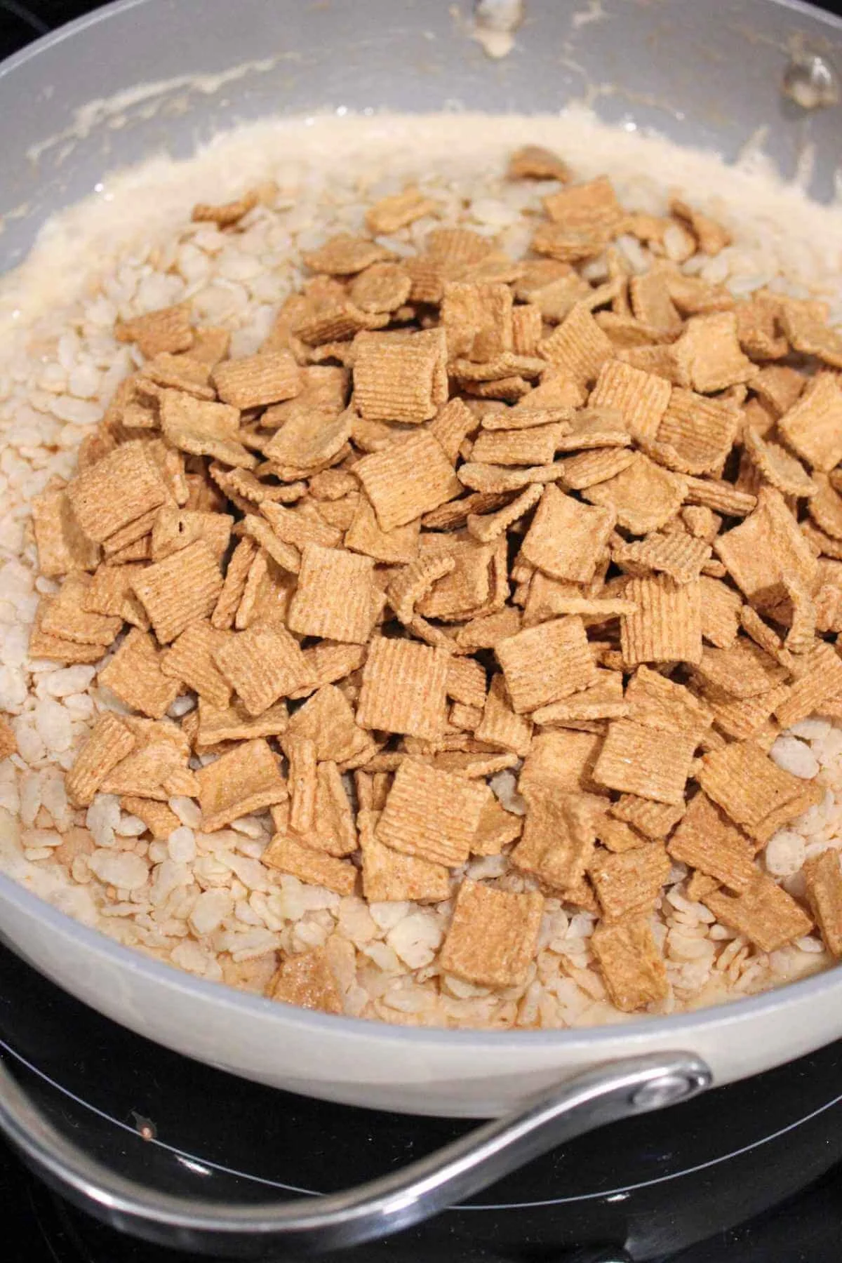 large pan with a marshmallow mixture topped with Rice Krispie cereal and golden grahams cereal.