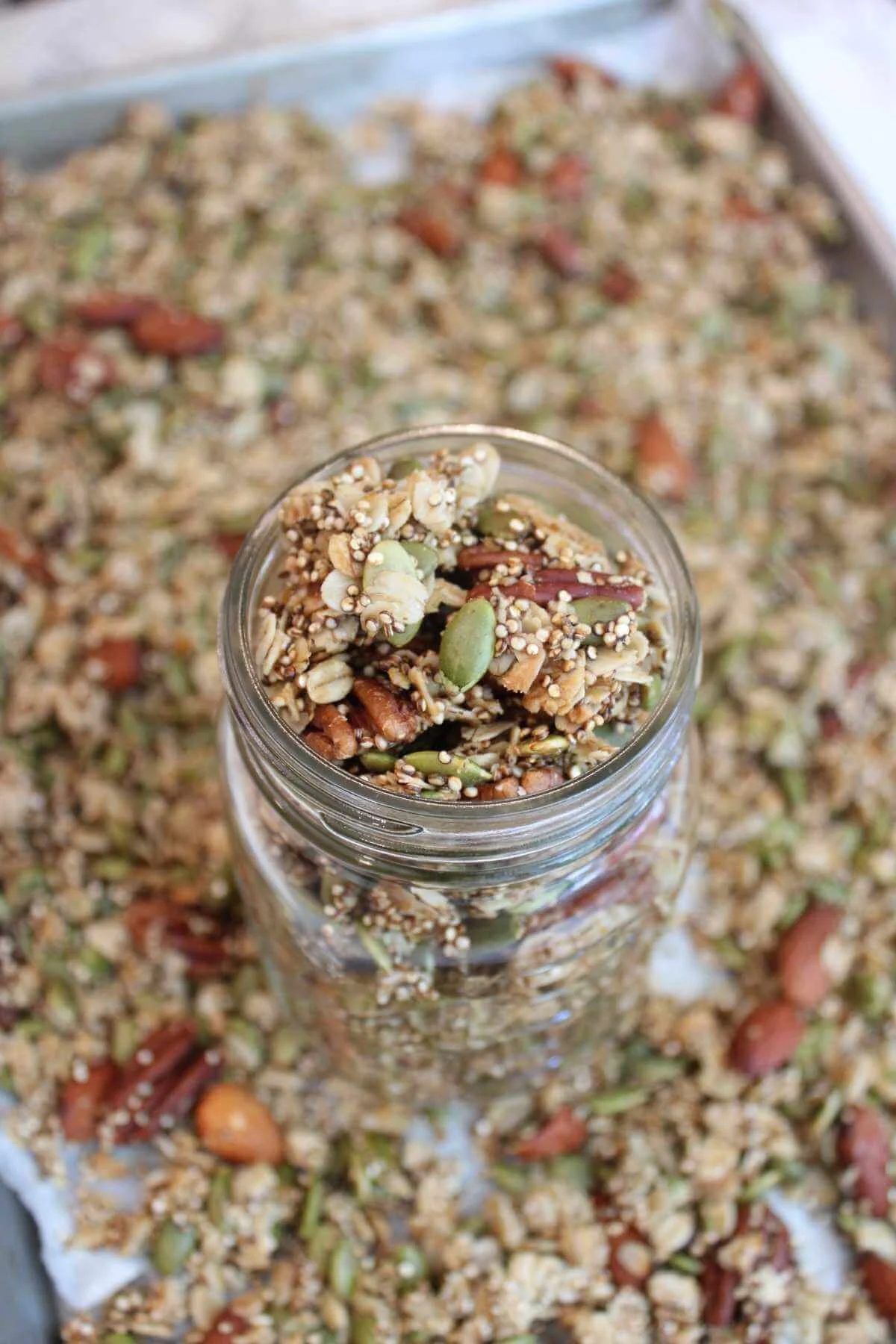 high protein granola recipe served in a glass paper jar on a baking tray of high protein granola.