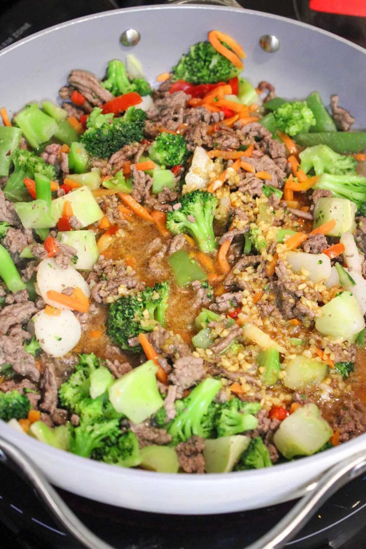 low sodium teriyaki sauce added to a pan of stir fry ground beef ingredients.