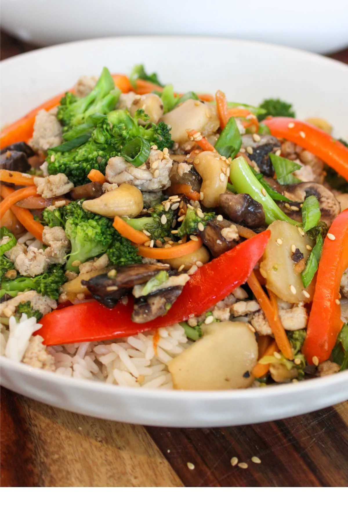 Ground chicken stir fry recipe served in a white bowl and topped with crunchy sesame seeds for garnish.
