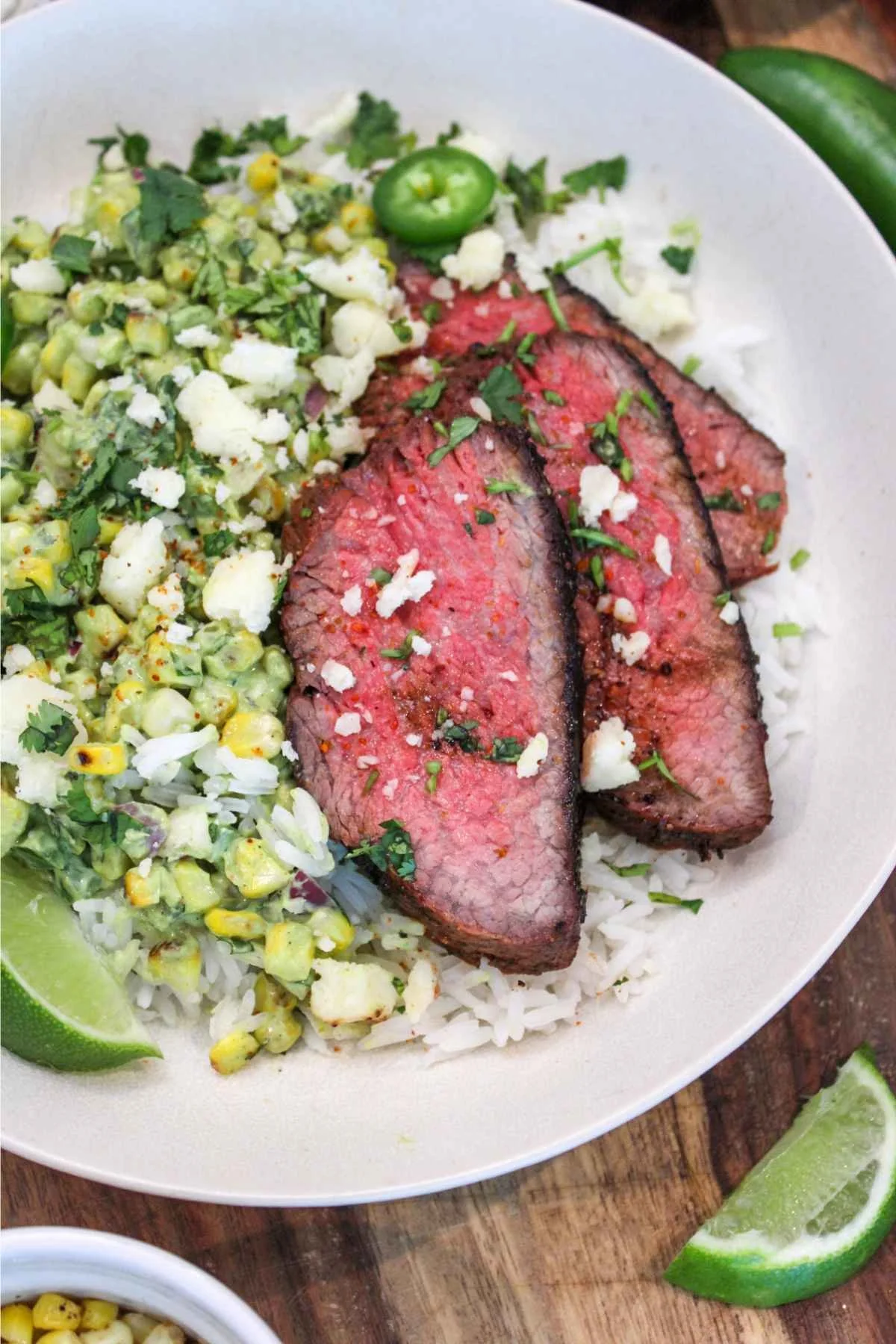 street corn paired with grilled tri-tip and served over cooked jasmine rice with a side of lime wedges.