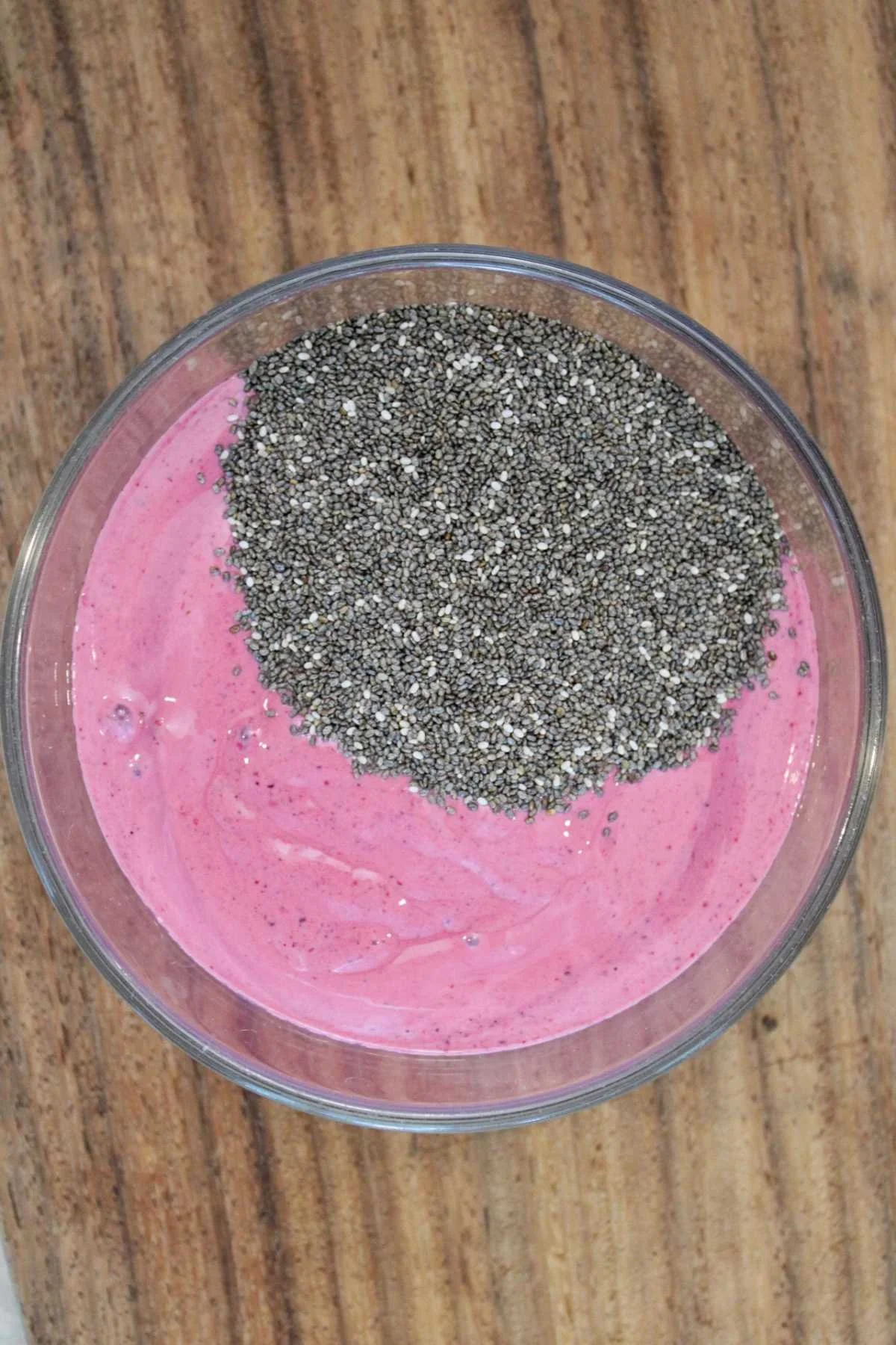 Glass jar containing a berry yogurt blend base with a scoop of chia seeds.