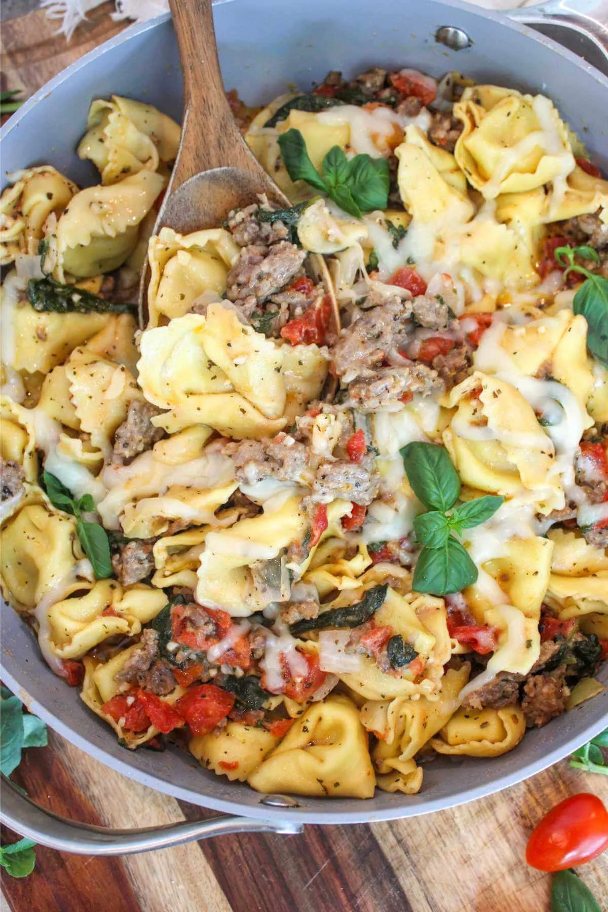 one pot sausage and tortellini recipe topped with fresh basil leaves and showcasing a spoonful of the easy dinner.