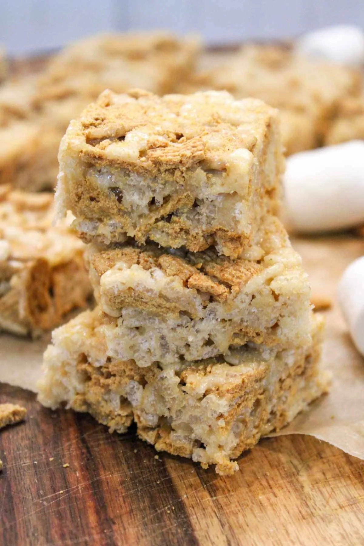 a stack of three rice krispie treats in front of a platter of Rice Krispies.