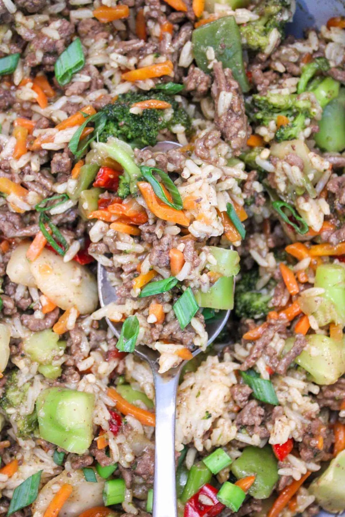A spoon full of stir fry with ground beef and rice, stir fry vegetables, and a homemade low sodium teriyaki sauce.