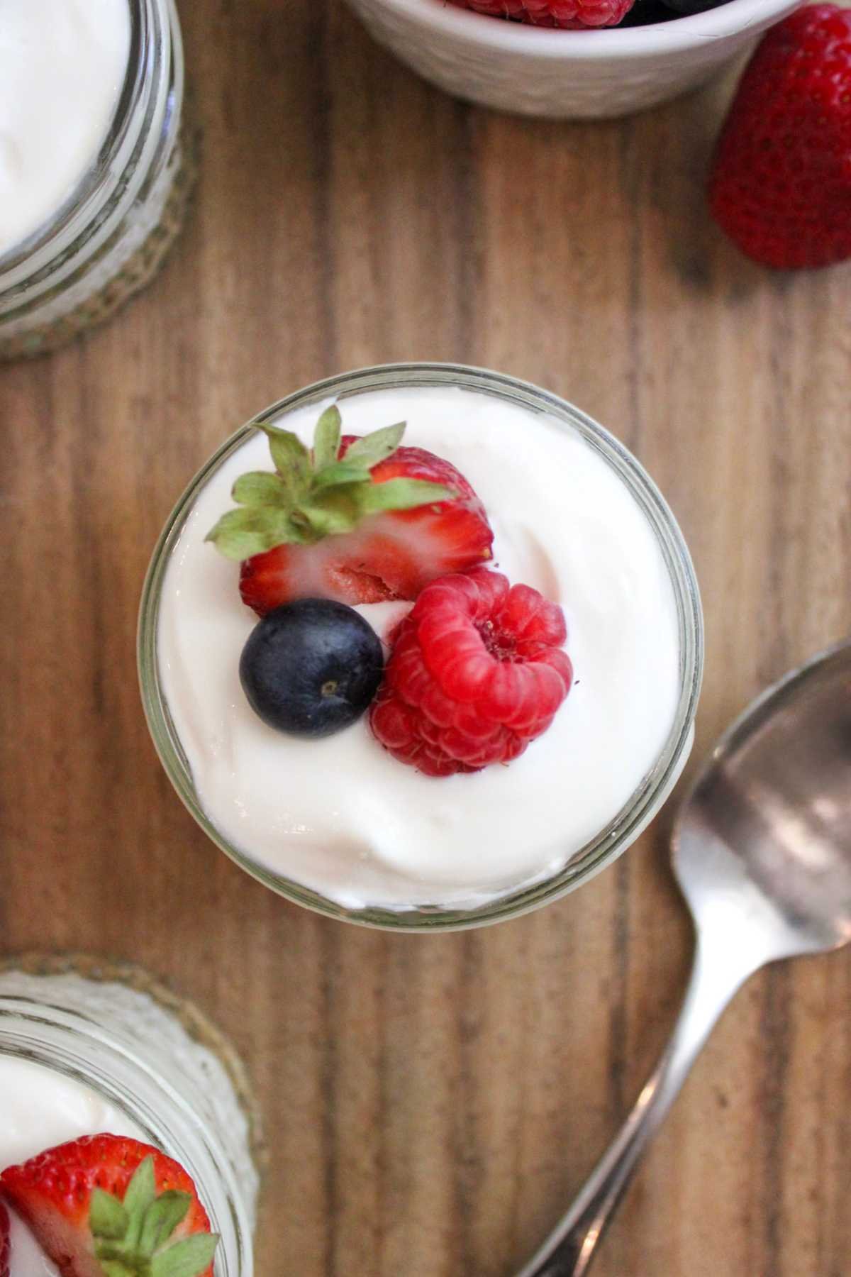 high protein cheesecake cups with spoon and fresh berries for toppings.