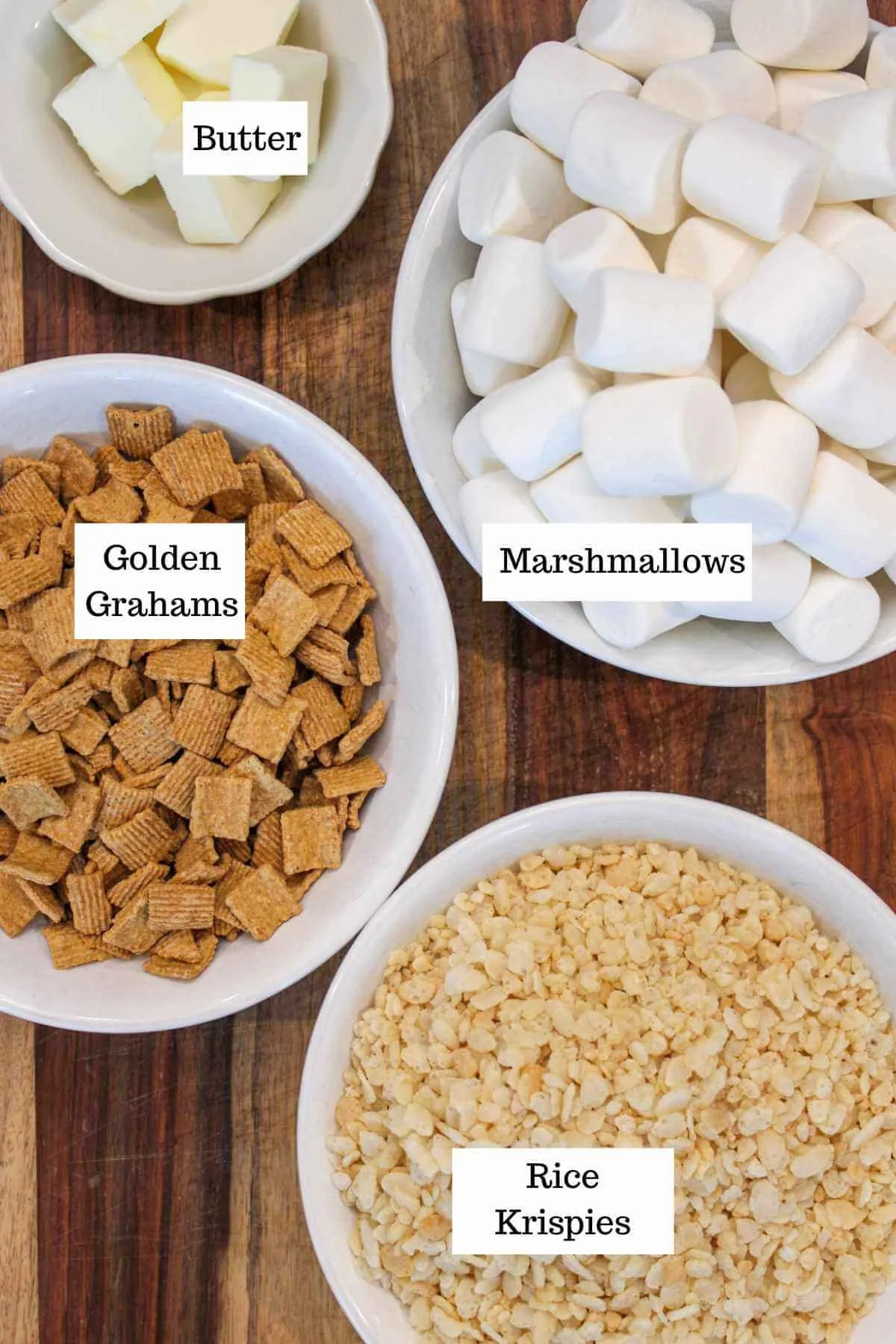 wooden board with 4 bowls of ingredients for brown butter rice krispie treats with golden grahams including marshmallows, Golden Grahams, rice cereal, and butter.