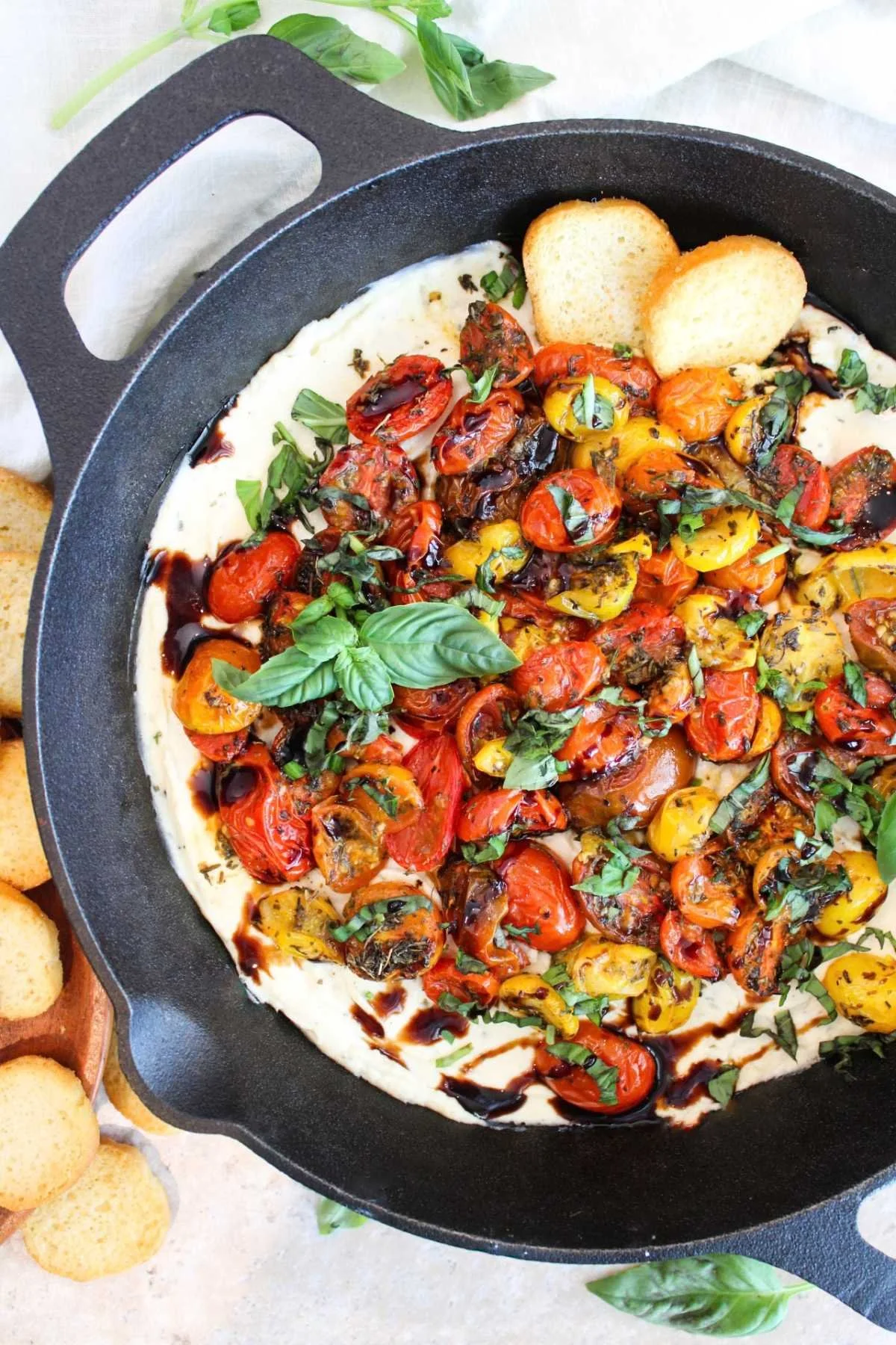 Cast iron pan with warm boursin dip and roasted tomatoes paired with crostinies.