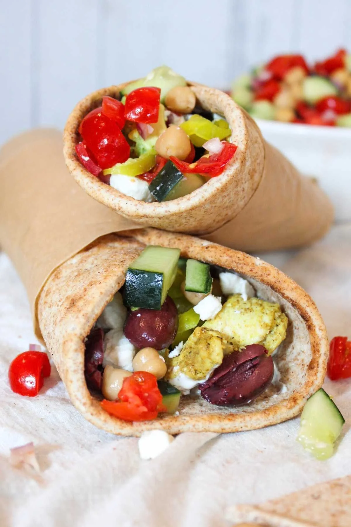 a stack of chicken pita wraps in whole wheat pita bread with Kalamata olives, chicken, cucumber, tomatoes, and feta cheese.