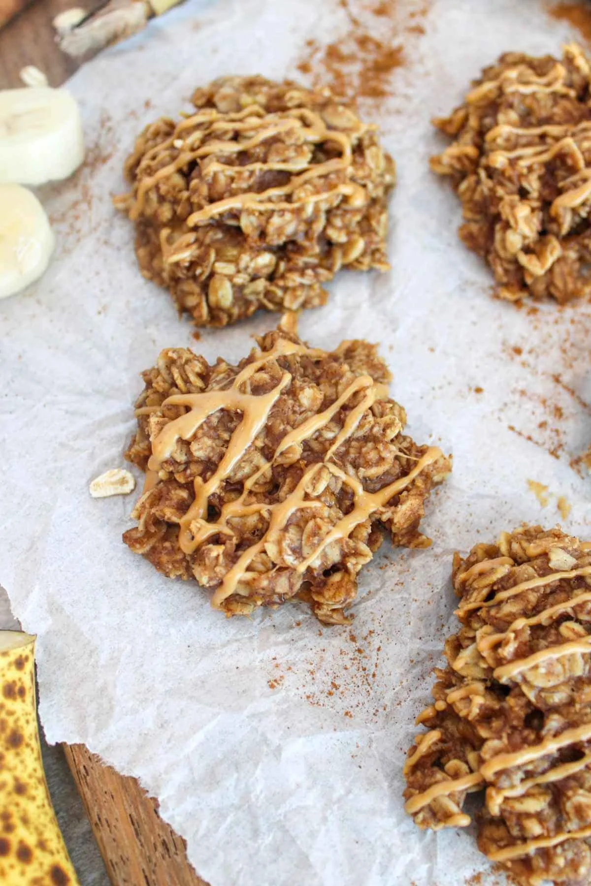 banana and oatmeal cookies on a piece of parchment paper than have been drizzled with a peanut butter drizzle.
