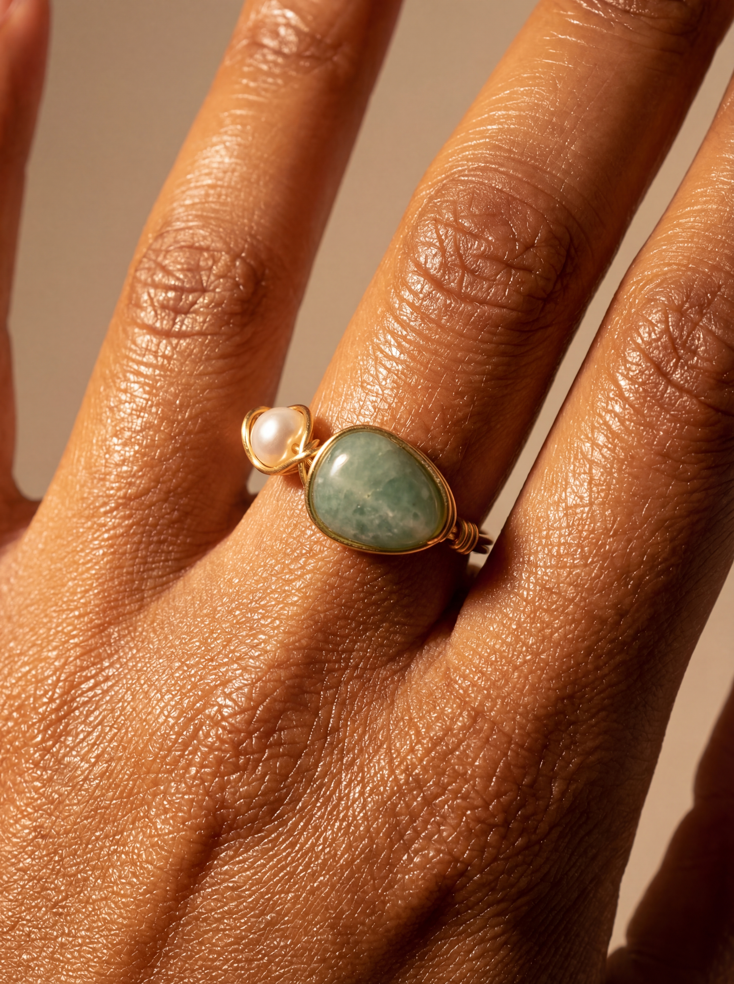 One green gemstone rings with yellow stones on a person's fingers, one with silver wire and the other with gold wire settings.