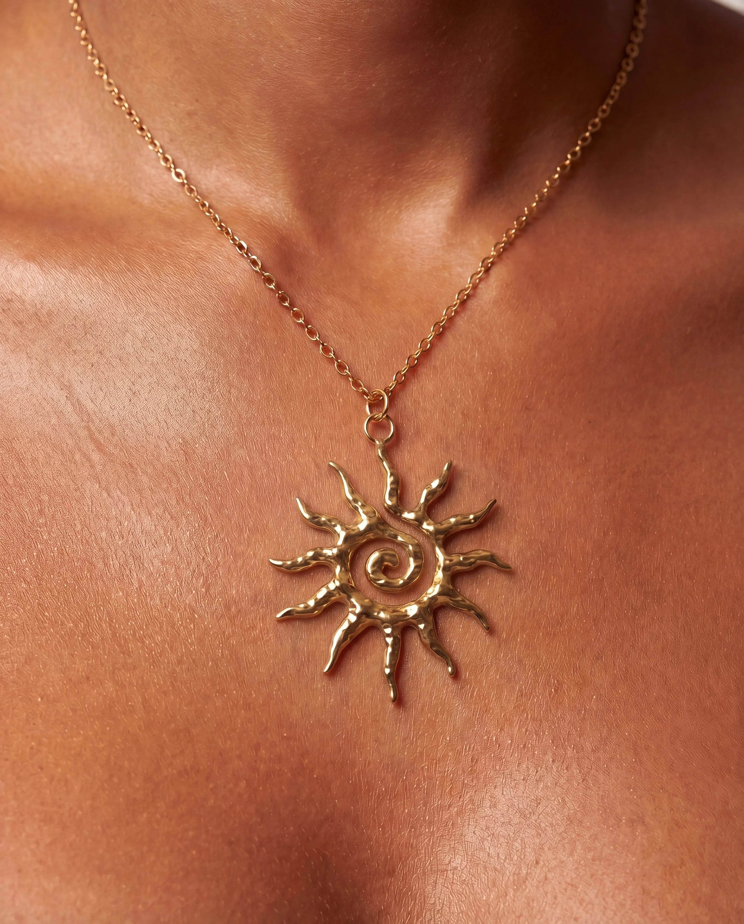 Close-up of a person wearing layered gold necklaces with various pendants, including a pearl, gemstone, and bead, over a white top.